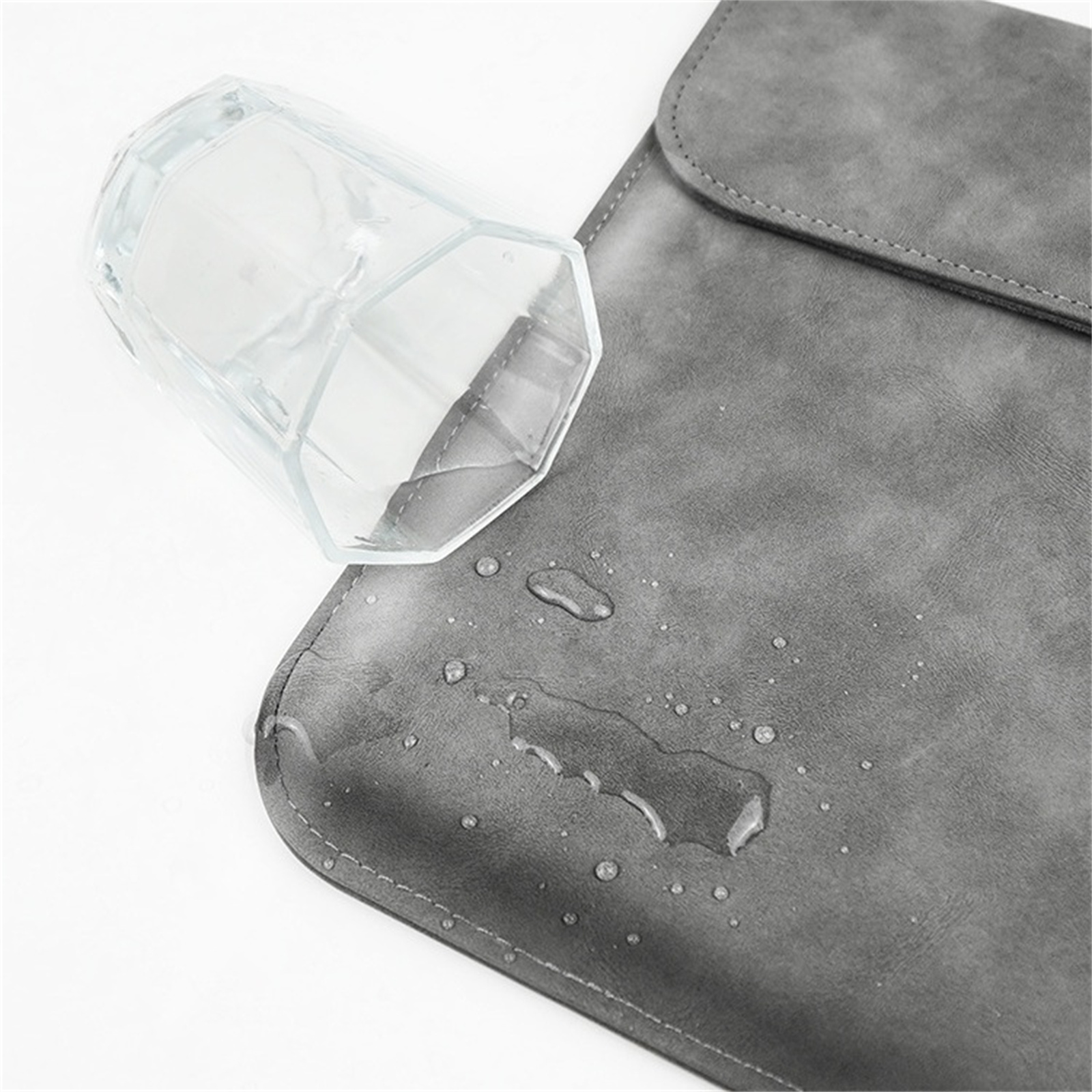 Ein Glas mit Wassertropfen steht auf einer grauen, wasserabweisenden Oberfläche. Die Oberfläche ist strukturiert.
