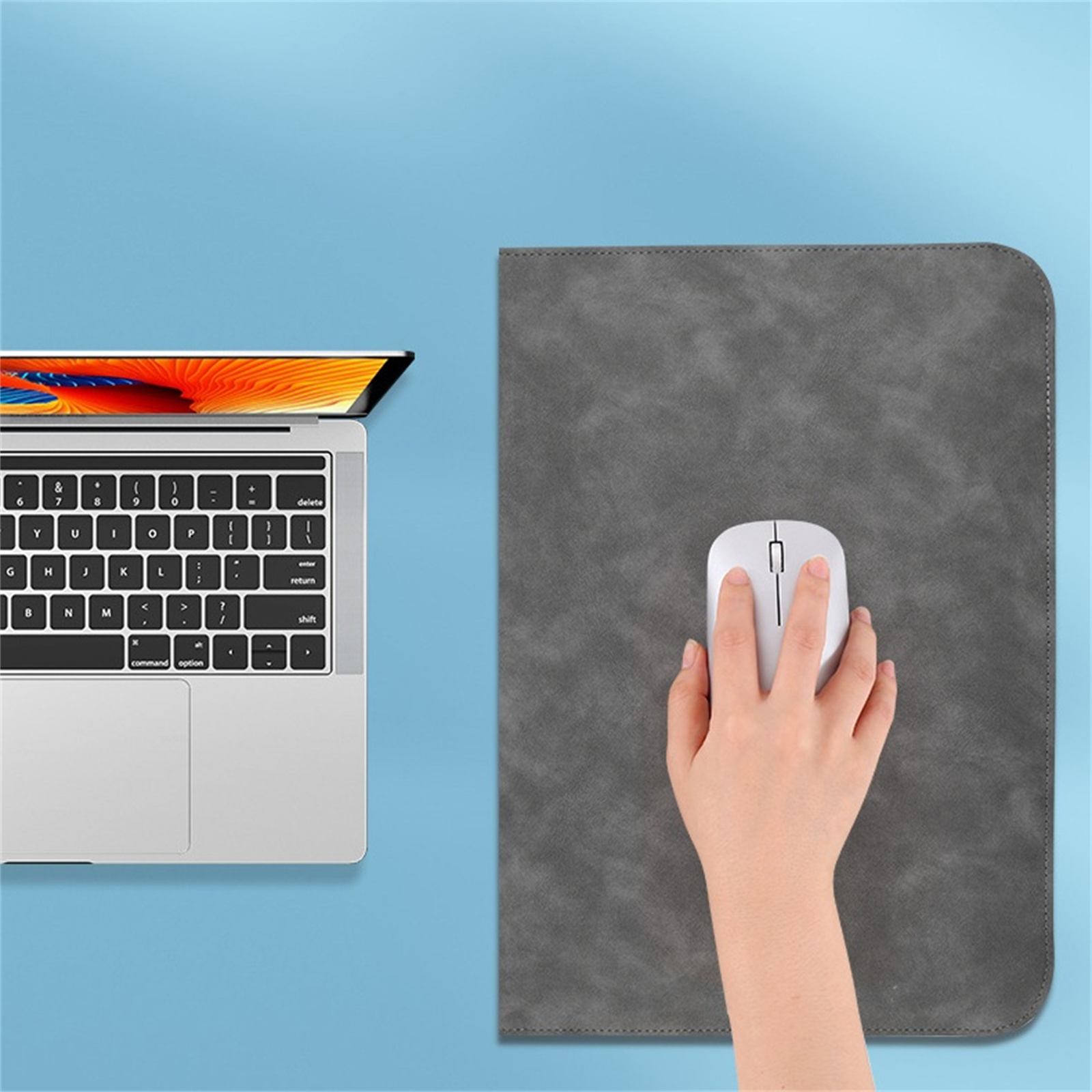 Laptop, Tastatur sichtbar, Maus auf grauem Mauspad, blauer Hintergrund.