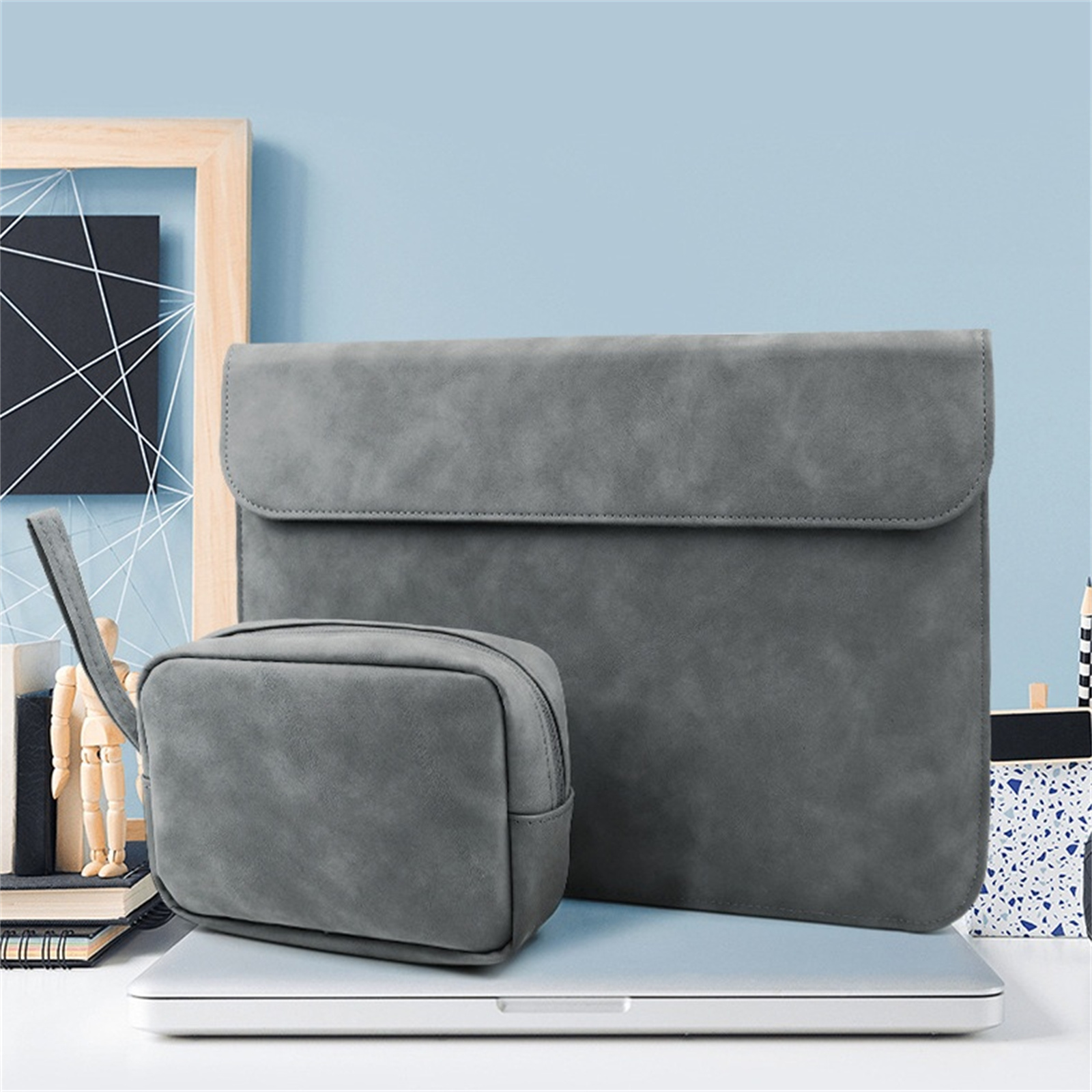 Zwei graue Laptoptaschen und ein Beutel auf einem Laptop vor blauem Hintergrund.