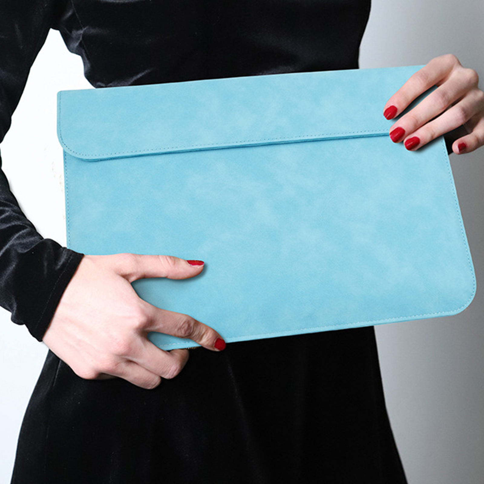 Eine Frau hält eine hellblaue Laptoptasche. Die Hülle hat ein schlichtes Design.