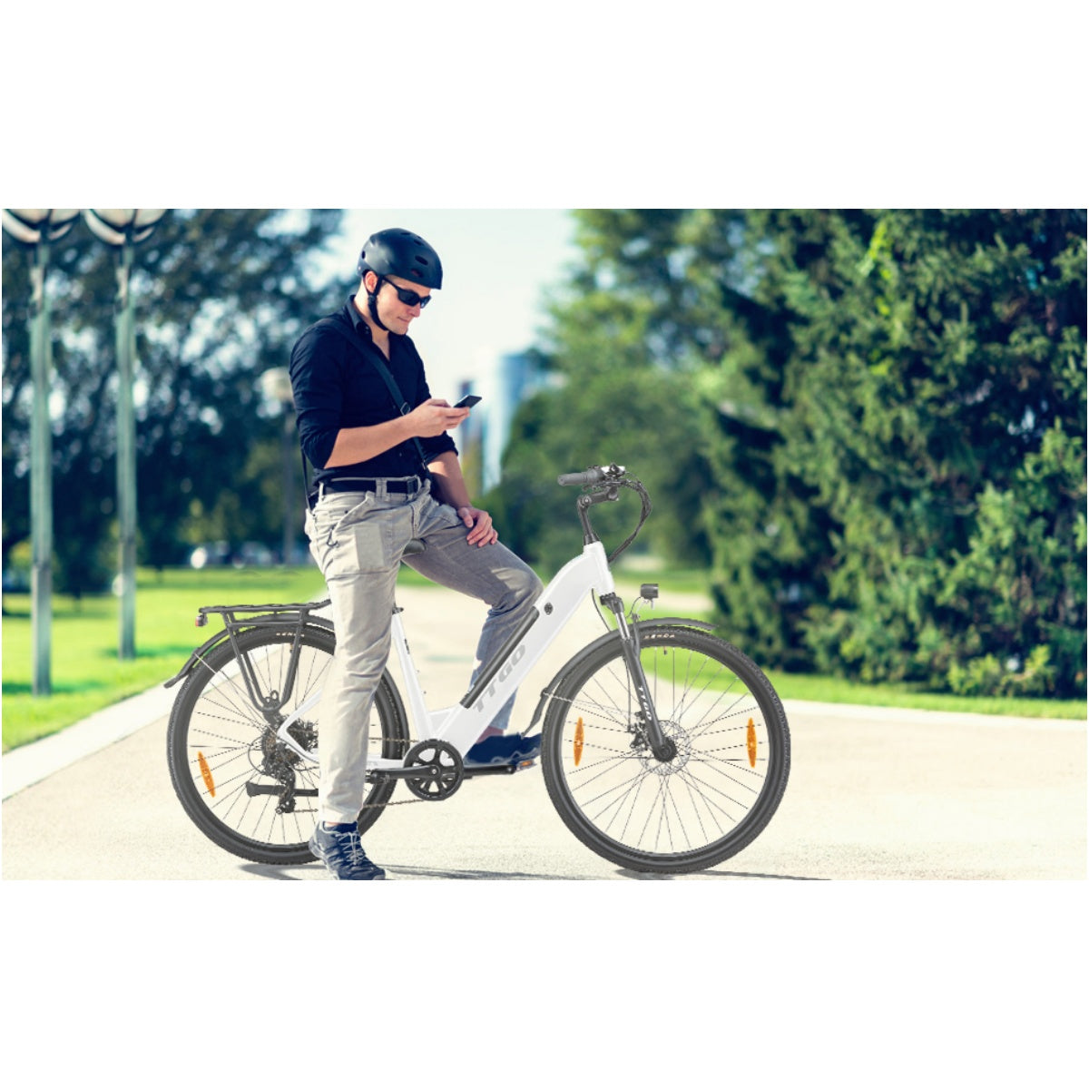 Ein Mann benutzt ein Telefon, während er neben einem weißen Elektrofahrrad auf einer Straße steht.