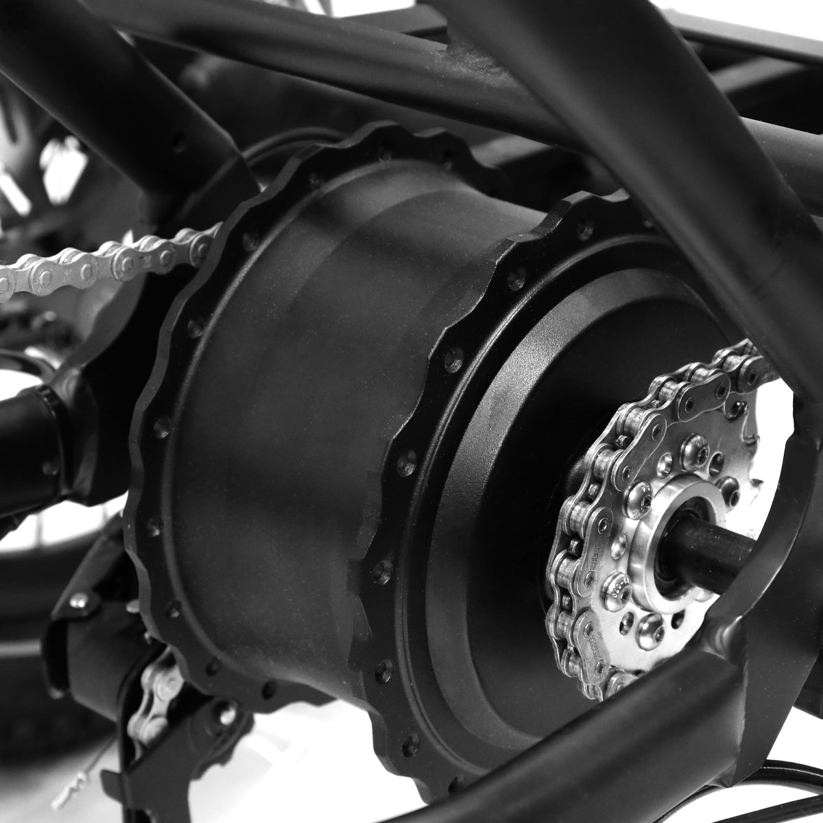 Primer plano de un motor de bicicleta eléctrica negro, con cadena y engranajes visibles. El motor es cilíndrico.