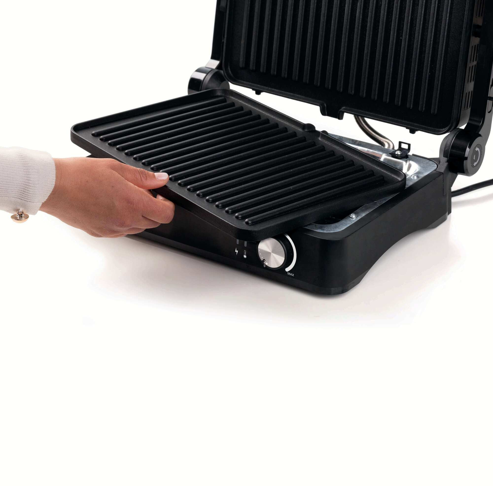 Eine Hand, die eine Grillplatte aus einer schwarzen Panini-Presse entfernt.