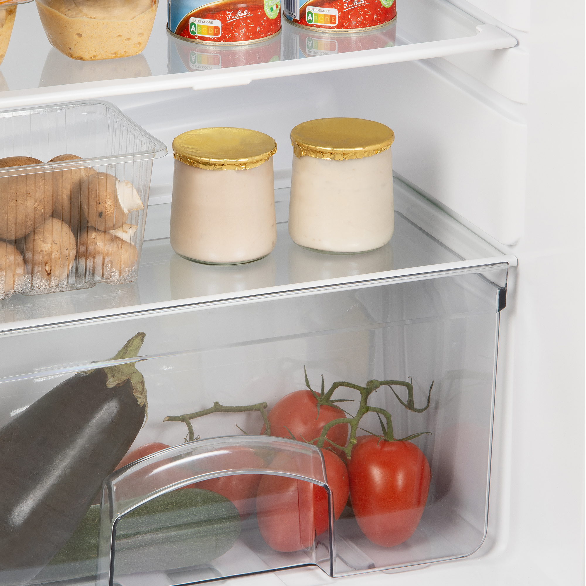 Intérieur de réfrigérateur avec de la nourriture. Il y a des tomates, du yaourt et des champignons dans des contenants.