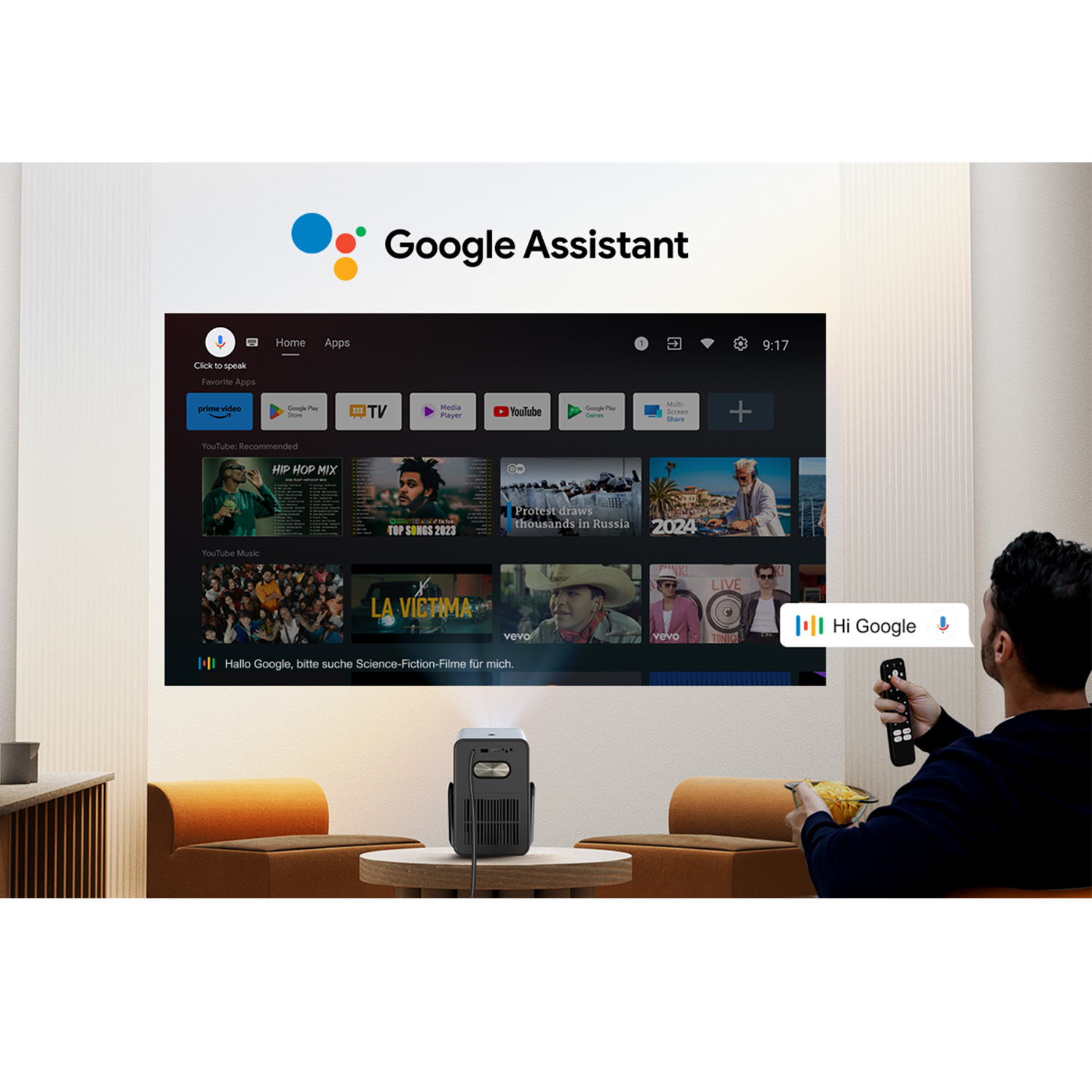 Een man gebruikt een afstandsbediening om een projector te bedienen die een tv-interface toont. Een zwarte projector staat op een tafel.