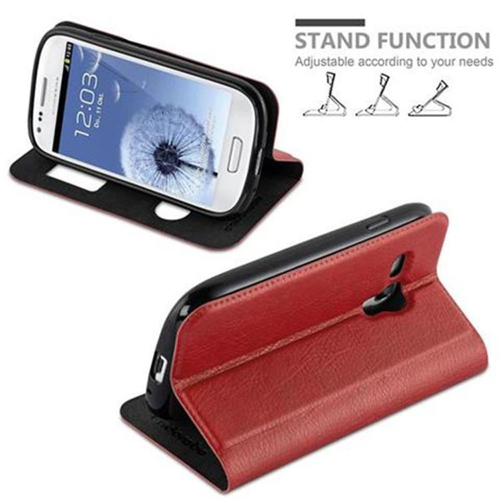 Un telefono in una custodia rossa è impostato con una funzione stand. Lo schermo mostra l'ora.