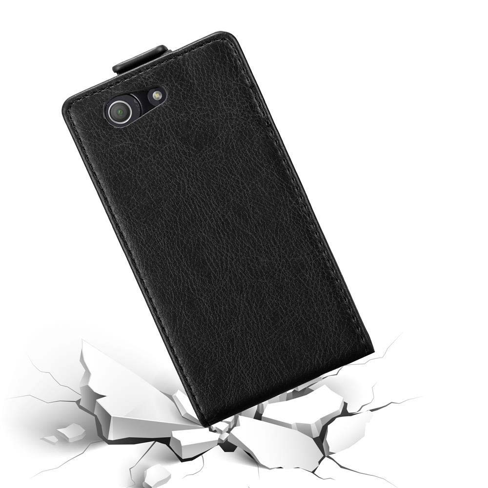 Funda de teléfono negra tipo flip en ángulo, sobre suelo agrietado.