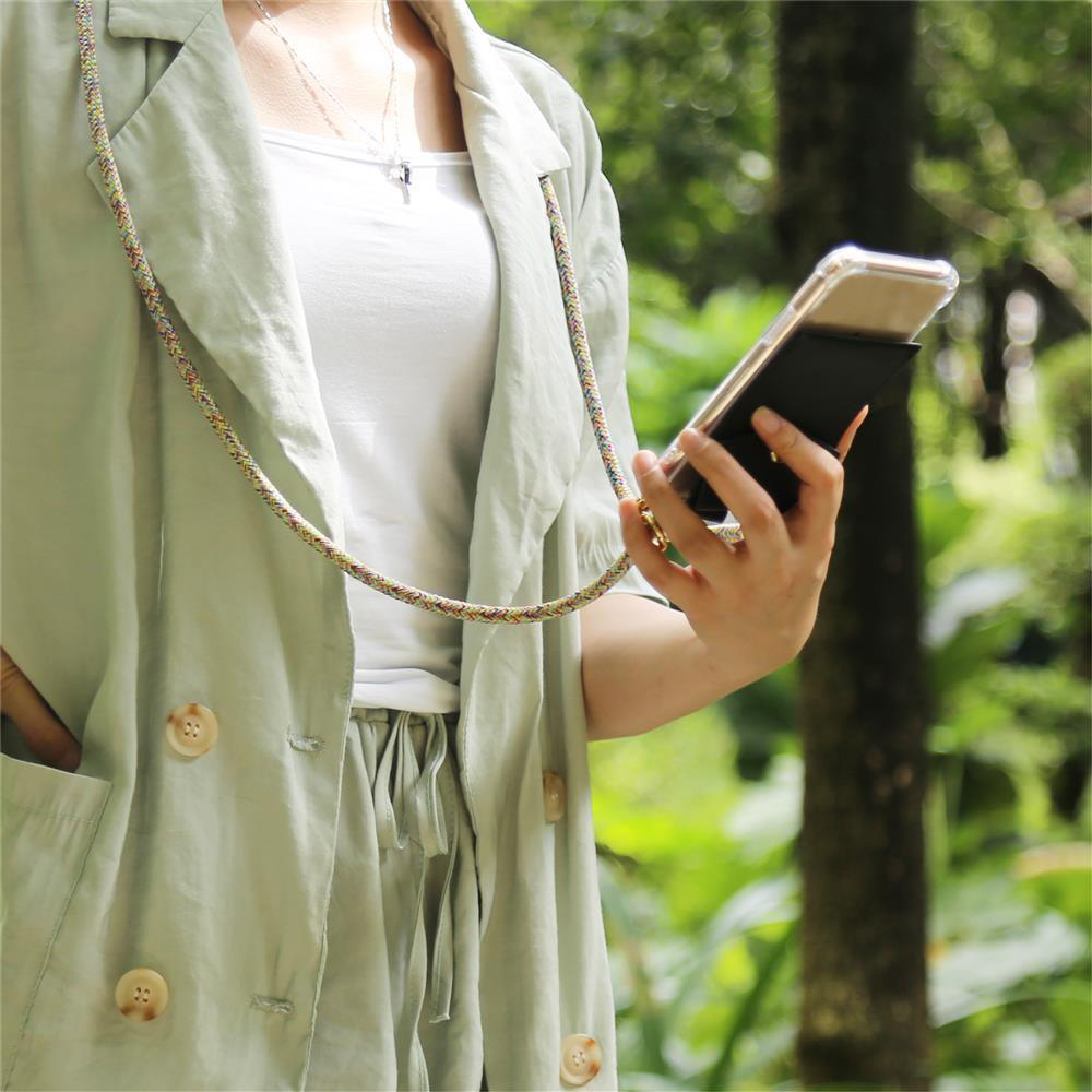 Una donna con un telefono appeso al collo. Il telefono è in una custodia nera con un cinturino.