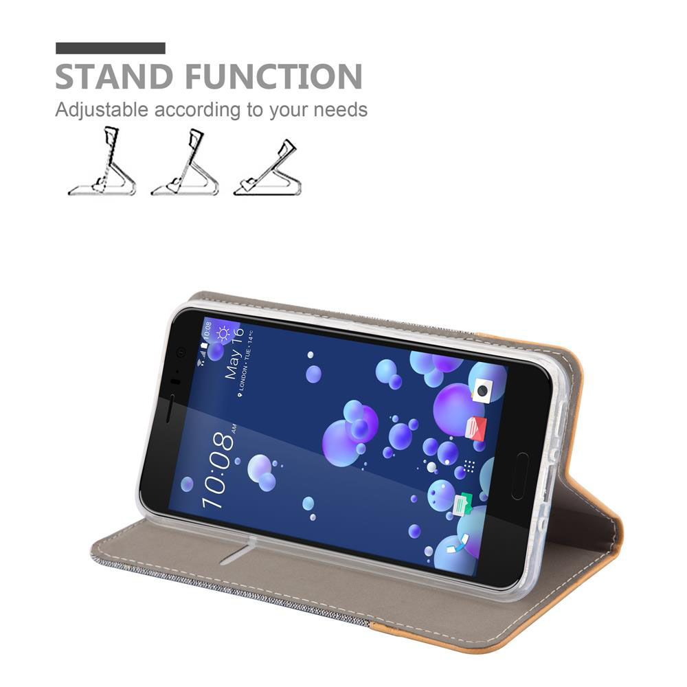 Telefono nella custodia, aperto. Mostra l'ora e la data sullo schermo. Funzione stand disponibile. Custodia grigia e arancione.