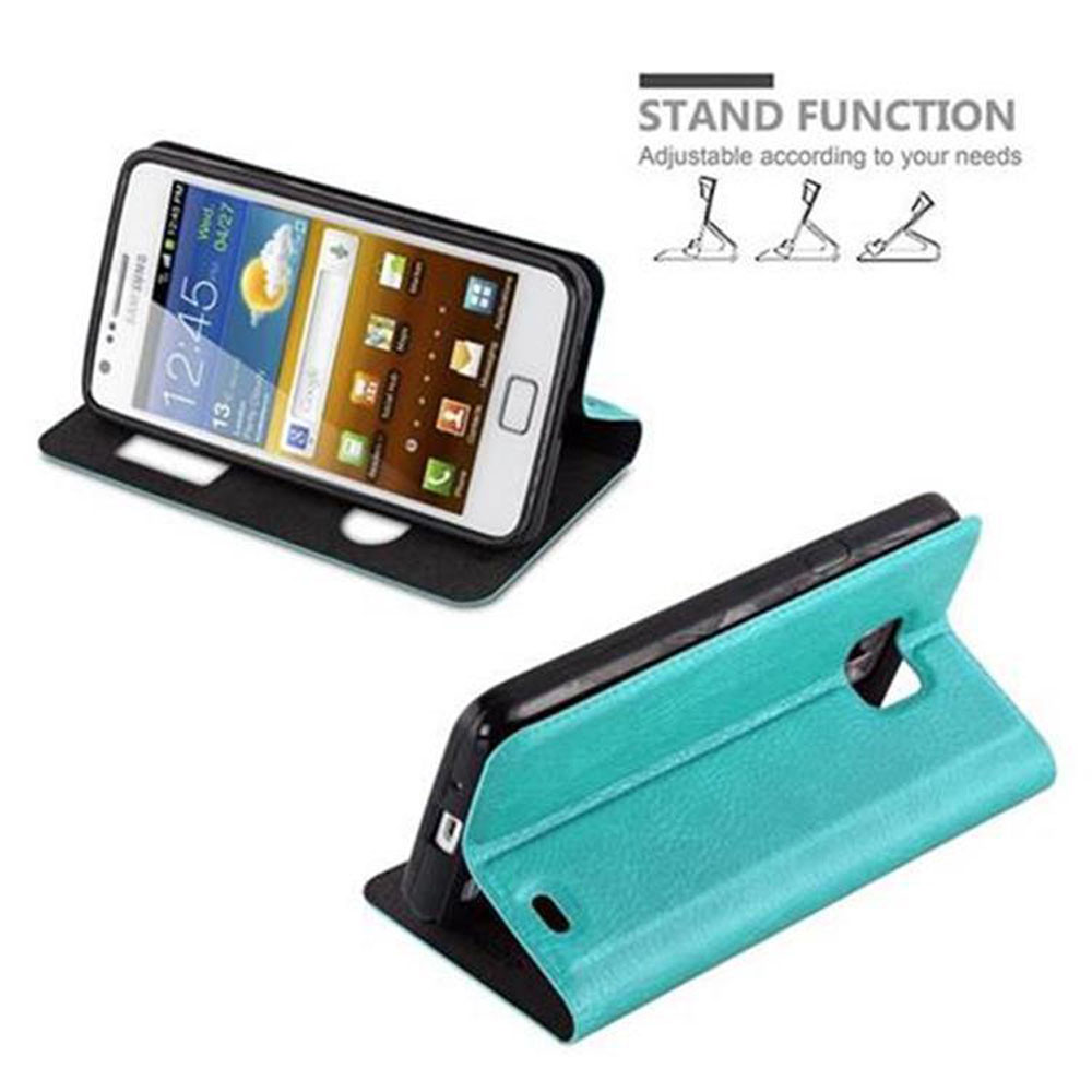 Teléfono en una funda abierto sobre una mesa. El texto dice: Función de soporte. La pantalla muestra la hora. Funda azul.