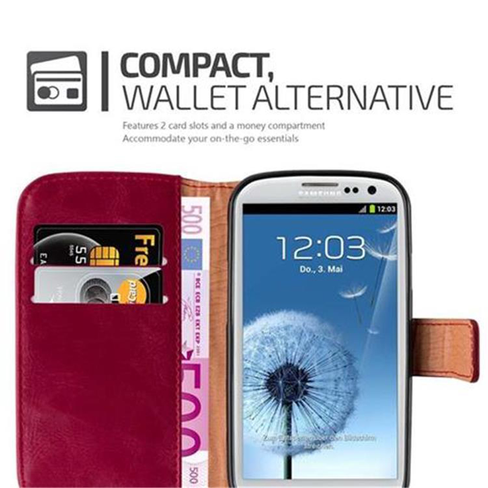 Un teléfono en un estuche de billetera rojo junto a dinero y tarjetas. La pantalla muestra la hora 12:03.