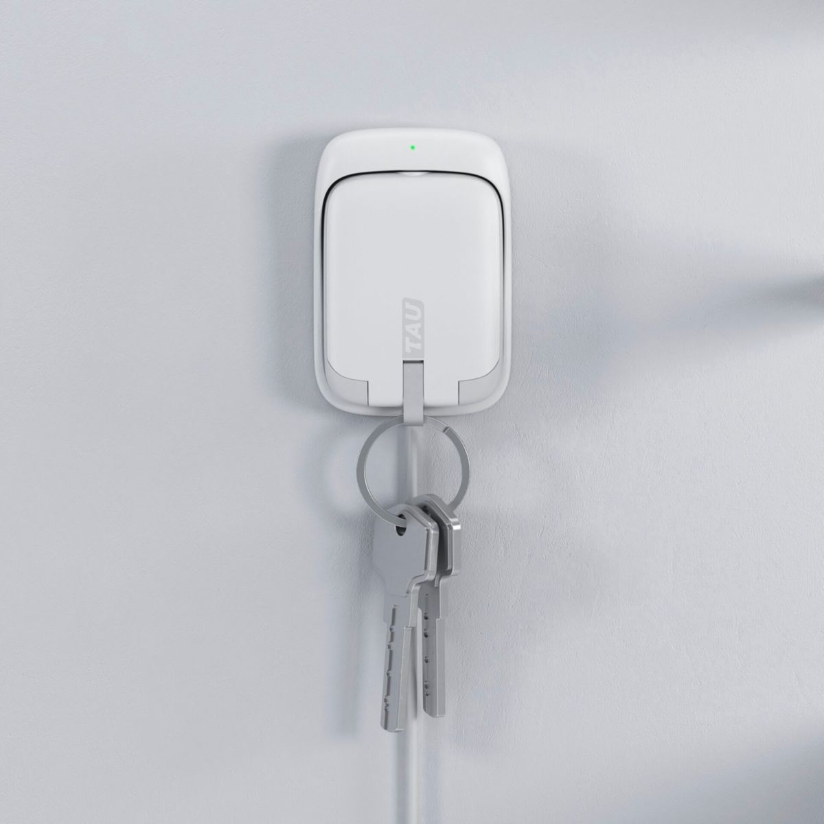 Porte-clés blanc sur un mur, avec clés suspendues. Le support est rectangulaire et porte la marque 'TAU'.