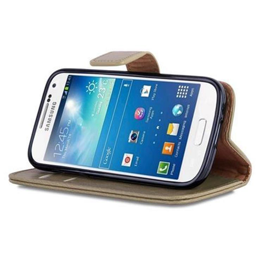 Un teléfono está en una funda y está apoyado. La pantalla muestra la hora, y la funda tiene una función de soporte.