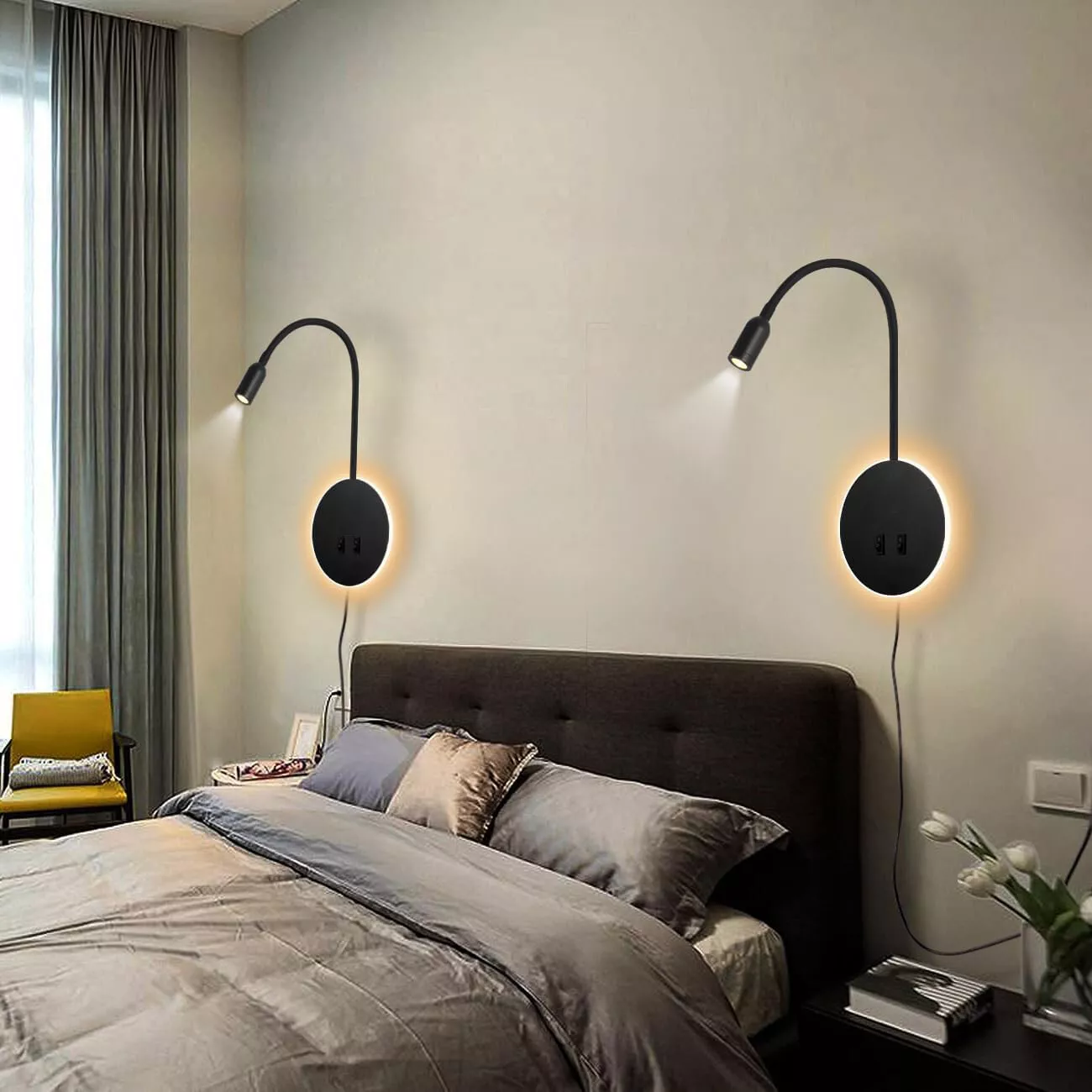 Ein Schlafzimmer mit zwei Wandlampen über dem Bett. Lampen sind schwarz mit warmweißem Licht.
