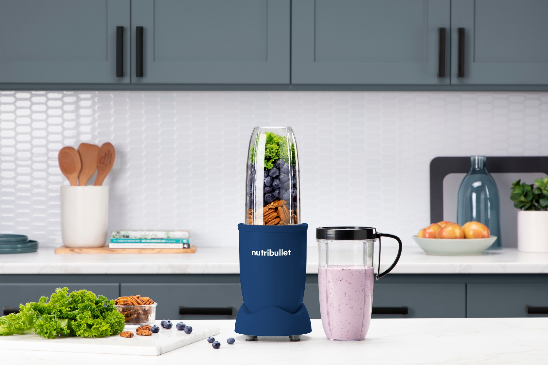 A blue blender with ingredients inside. The background includes a kitchen with blue cabinets.