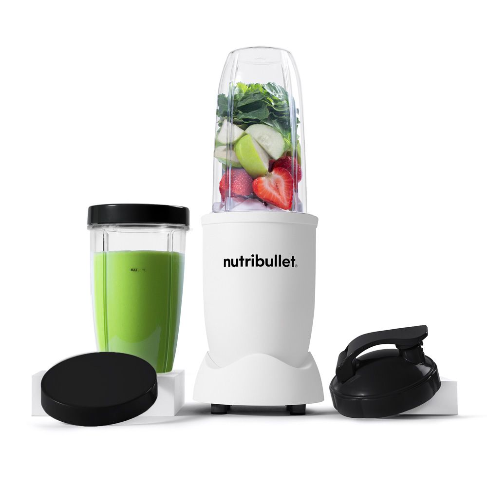 Een witte Nutribullet-blender met een beker groene smoothie en accessoires op een wit oppervlak.