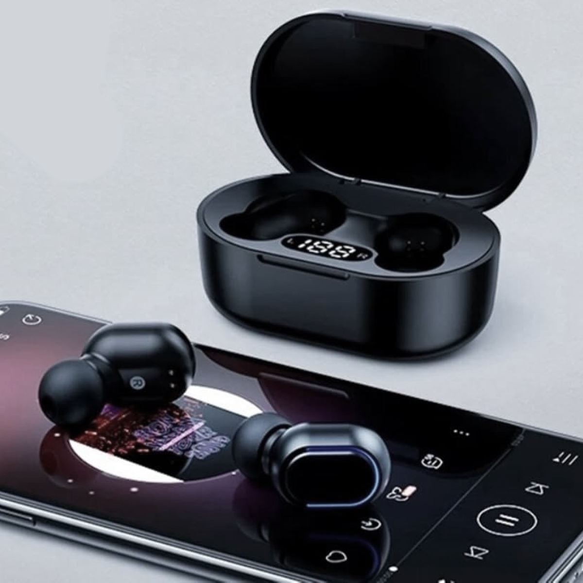 Schwarze kabellose Ohrhörer und Ladecase auf einem Smartphone, das eine Musik-App anzeigt. Das Case ist offen und zeigt die Ohrhörer und ein Display.