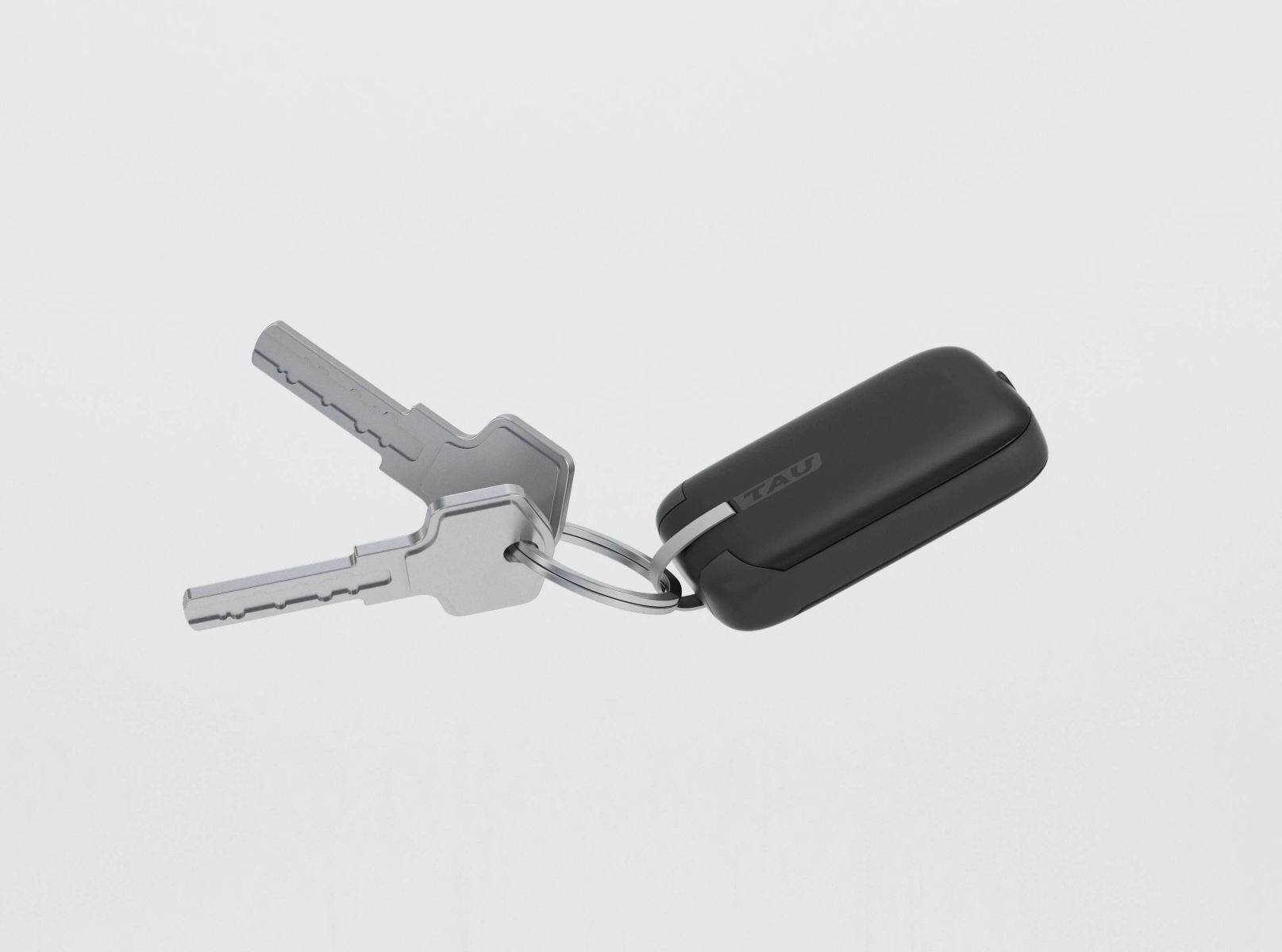 Sleutels aan een sleutelring met een zwarte sleutelhanger. De sleutels zijn zilverkleurig, de sleutelhanger is zwart met 'TAU'.