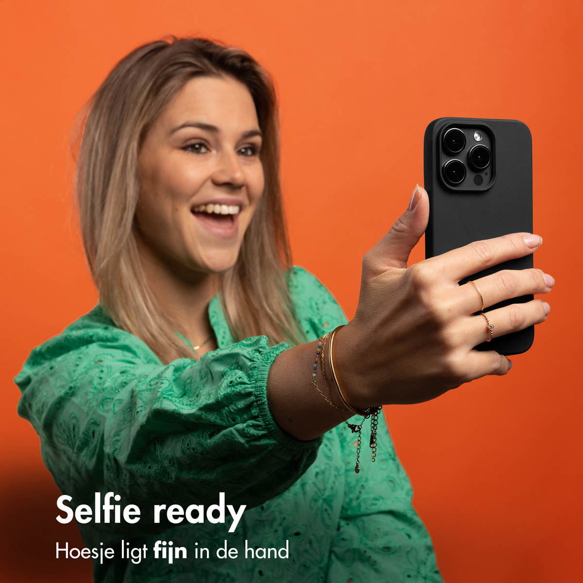 Eine Frau macht ein Selfie mit einer schwarzen Handyhülle. Der Hintergrund ist orange.