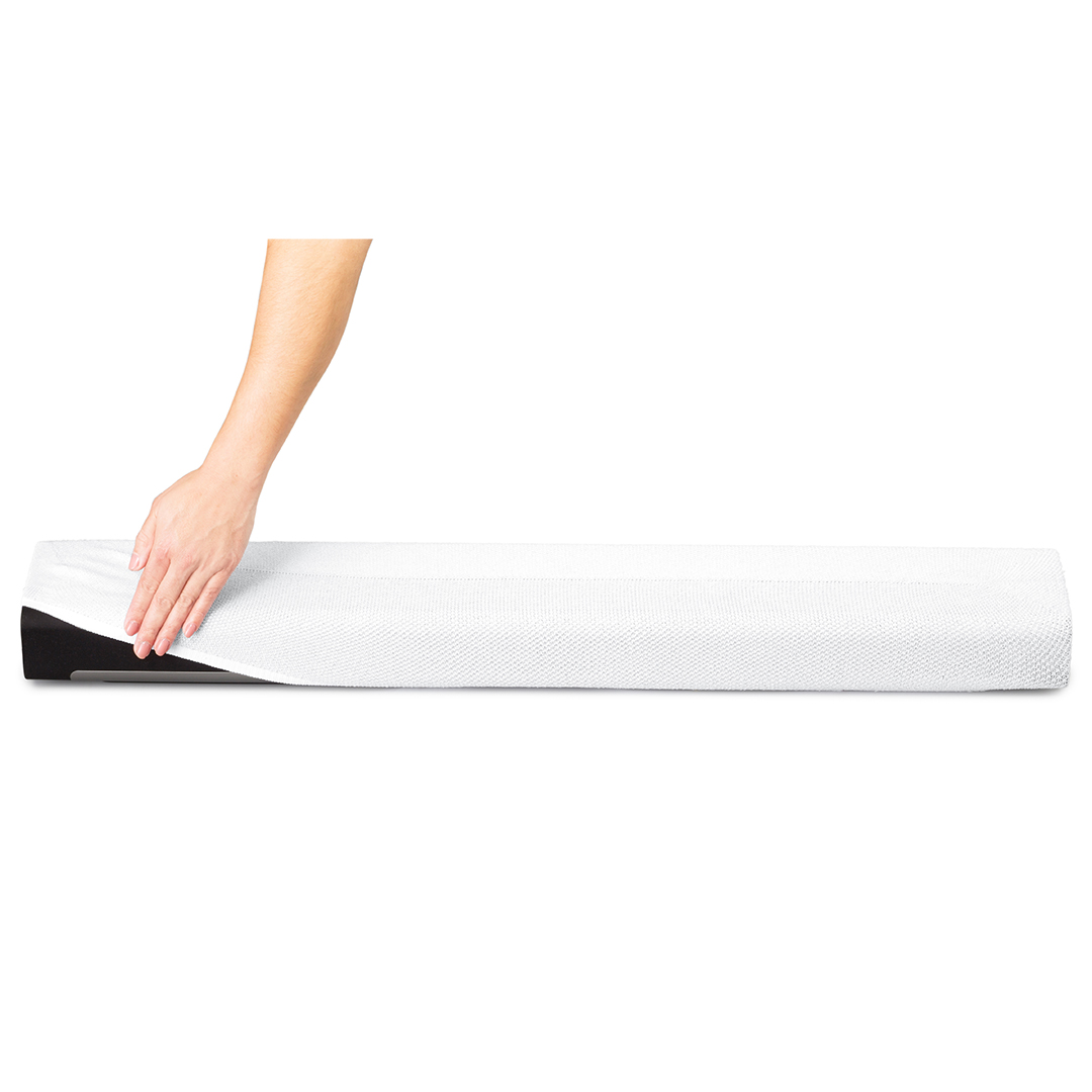 Main plaçant une couverture blanche sur un objet noir et rectangulaire. Fond blanc.
