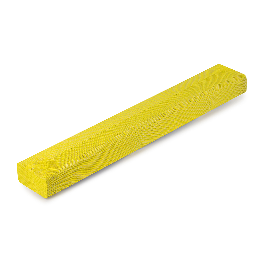 Bloc de mousse rectangulaire jaune sur une surface blanche. Le bloc est texturé uniformément et solide.
