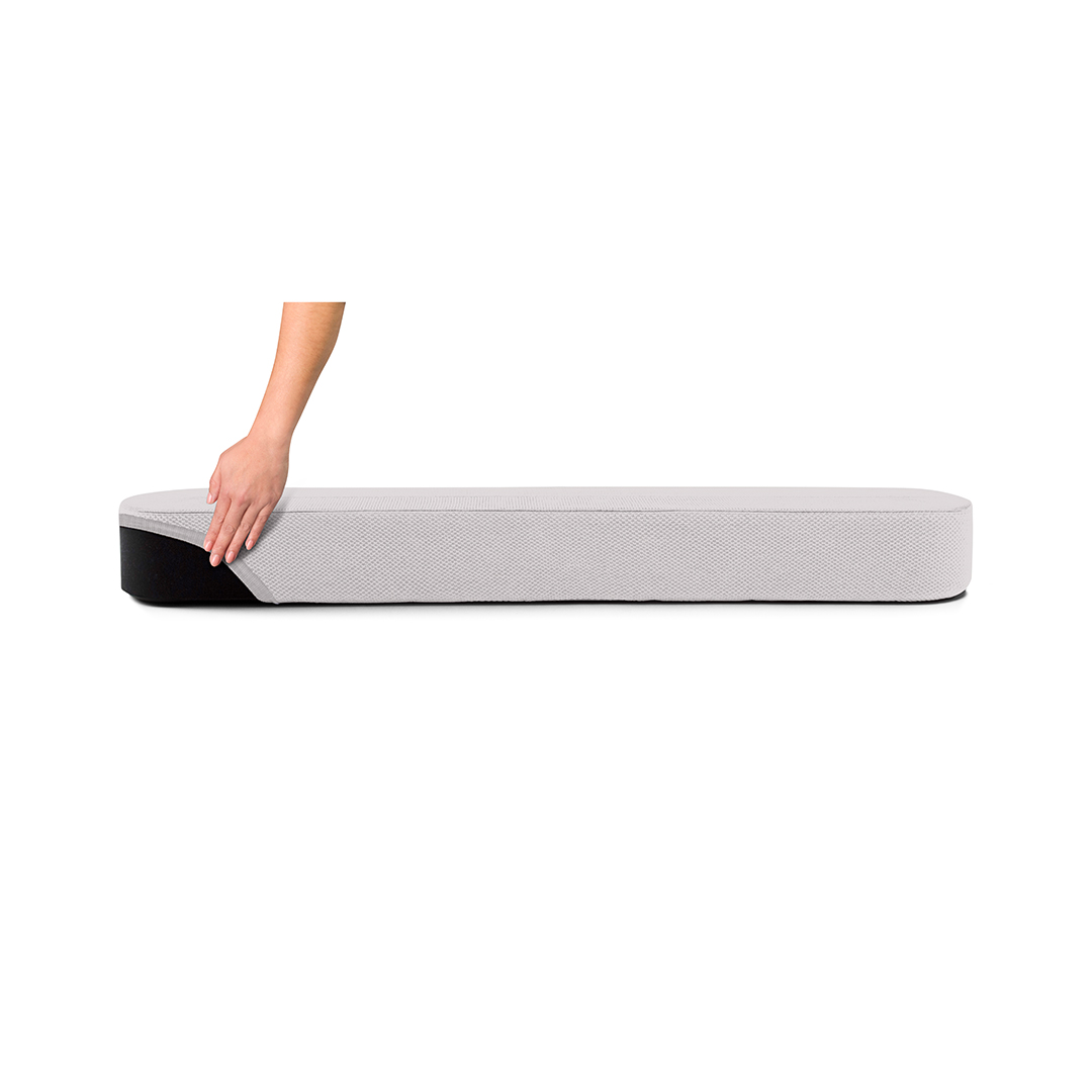 Main touchant un matelas gris sur fond blanc.