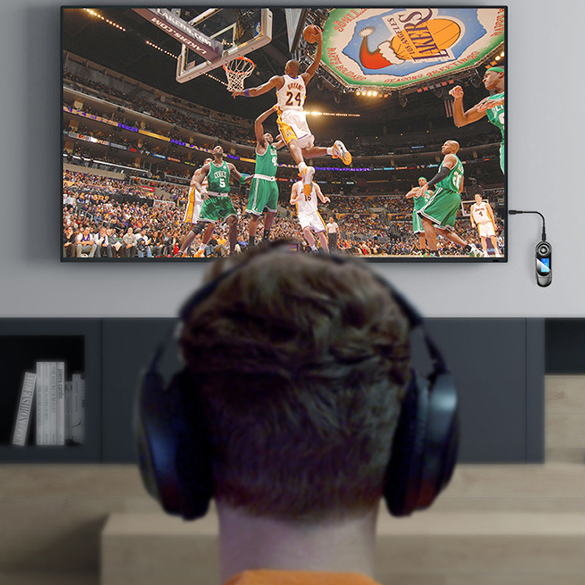 Person schaut Basketballspiel auf TV, mit Kopfhörern, dunkler Hintergrund.