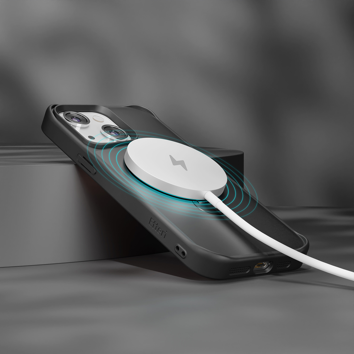 Schwarzes Telefon in schwarzer Hülle, kabellos mit weißem magnetischen Ladegerät geladen. Grauer Hintergrund.