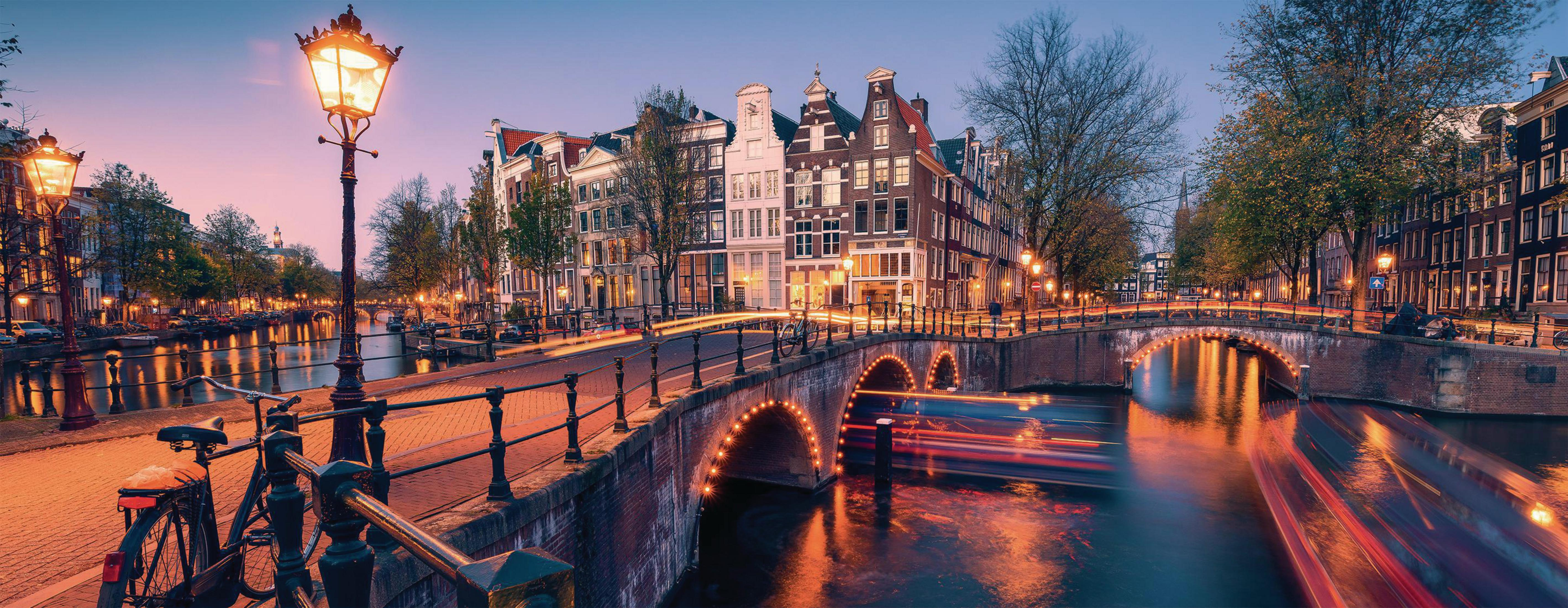 Panorama von Amsterdam in der Abenddämmerung mit Kanälen, Brücken, Straßenlaternen und Gebäuden.