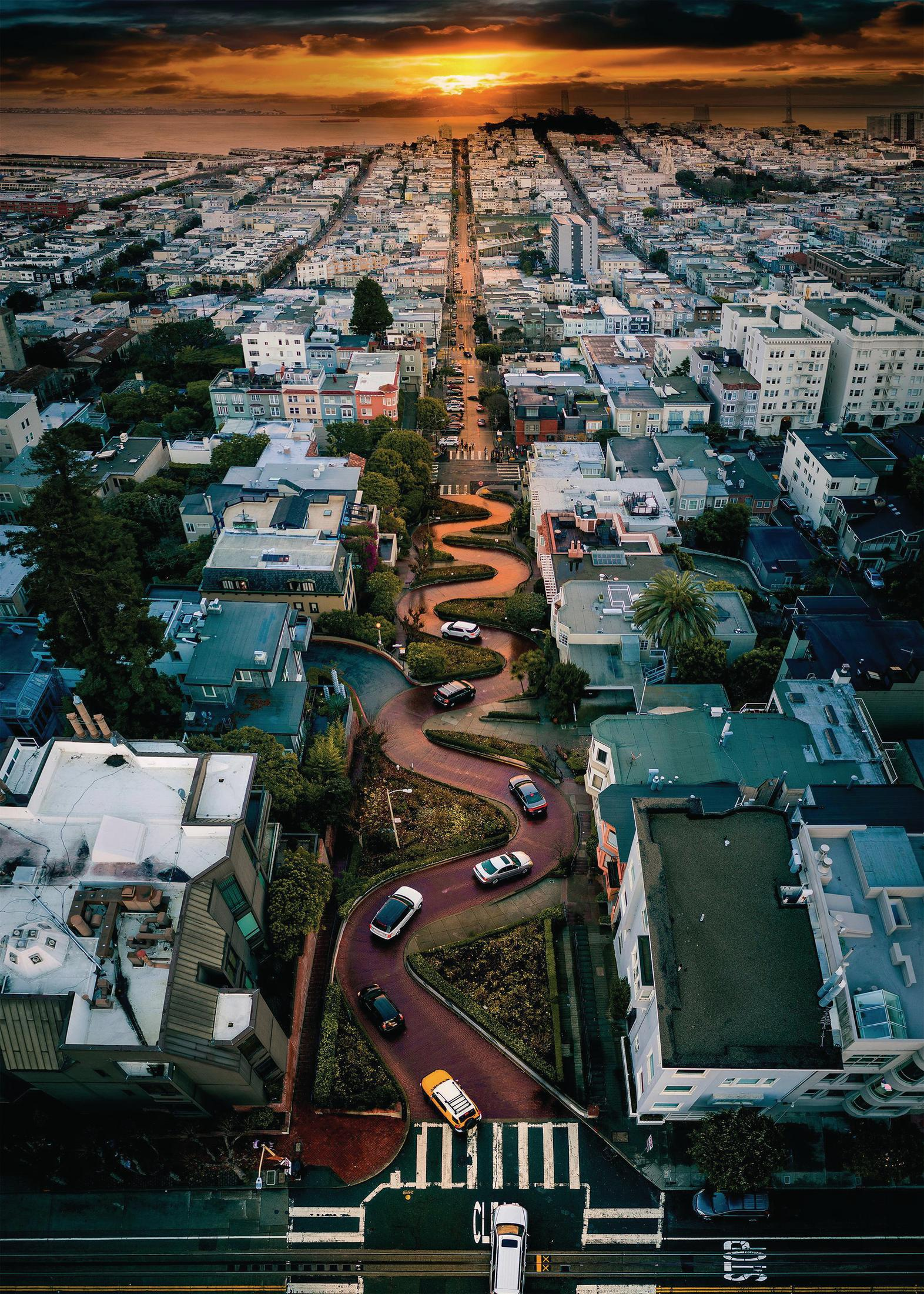 Luftaufnahme der Lombard Street in San Francisco bei Sonnenuntergang, mit Autos und Gebäuden.
