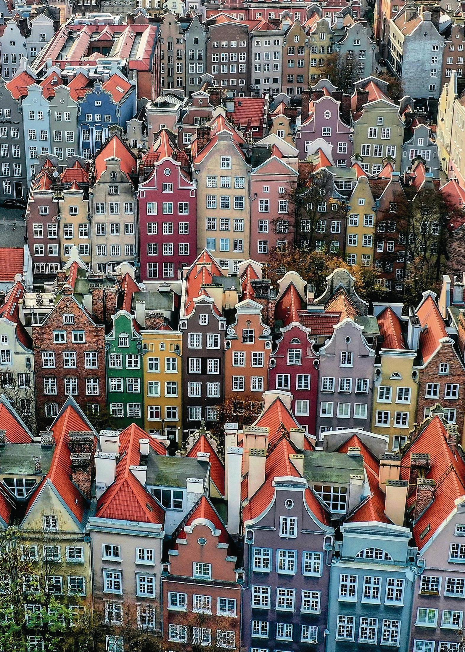 Draufsicht auf bunte Gebäude mit roten Dächern in einer europäischen Stadt.