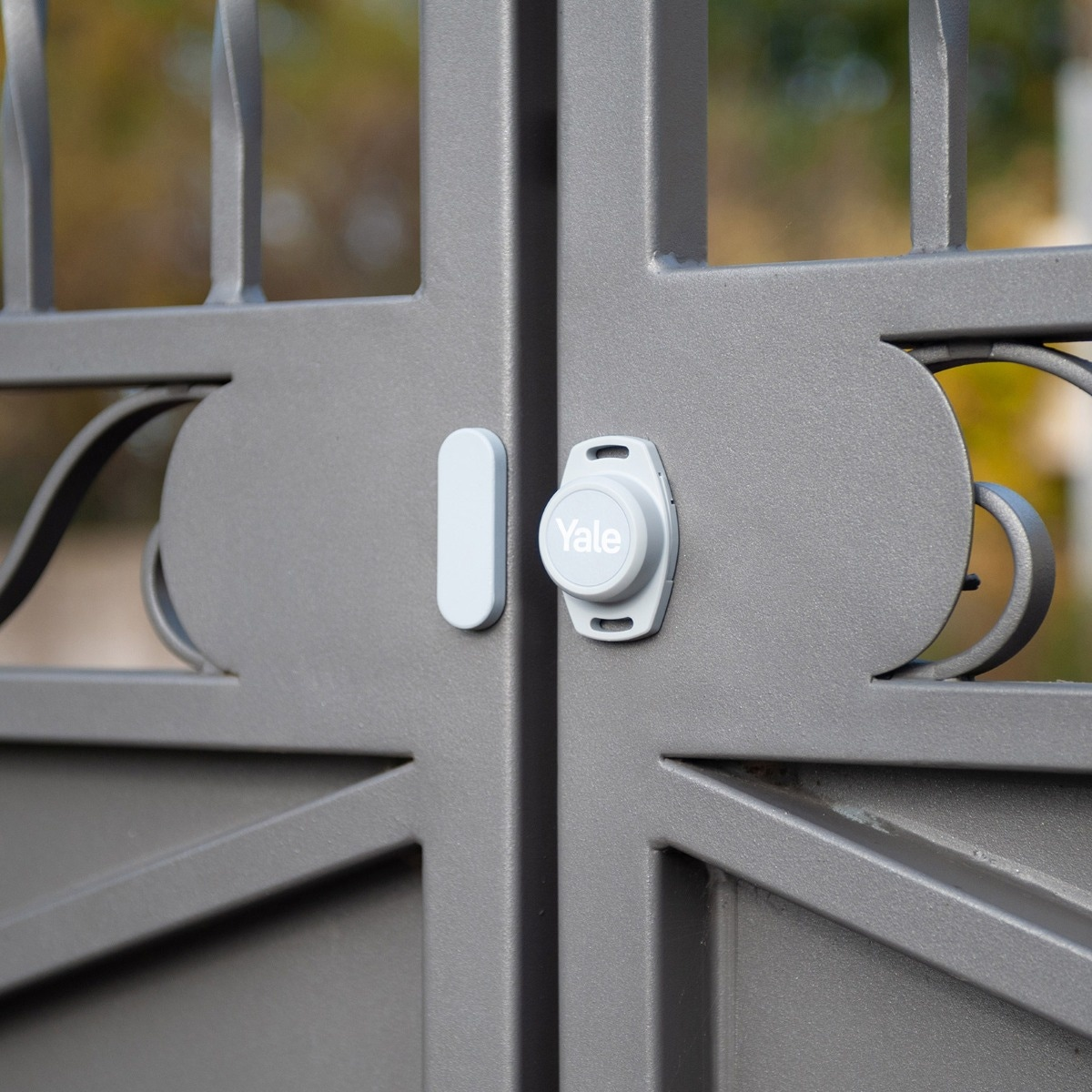 Una cerradura inteligente Yale está instalada en una puerta gris. Se adjunta un módulo de control blanco.
