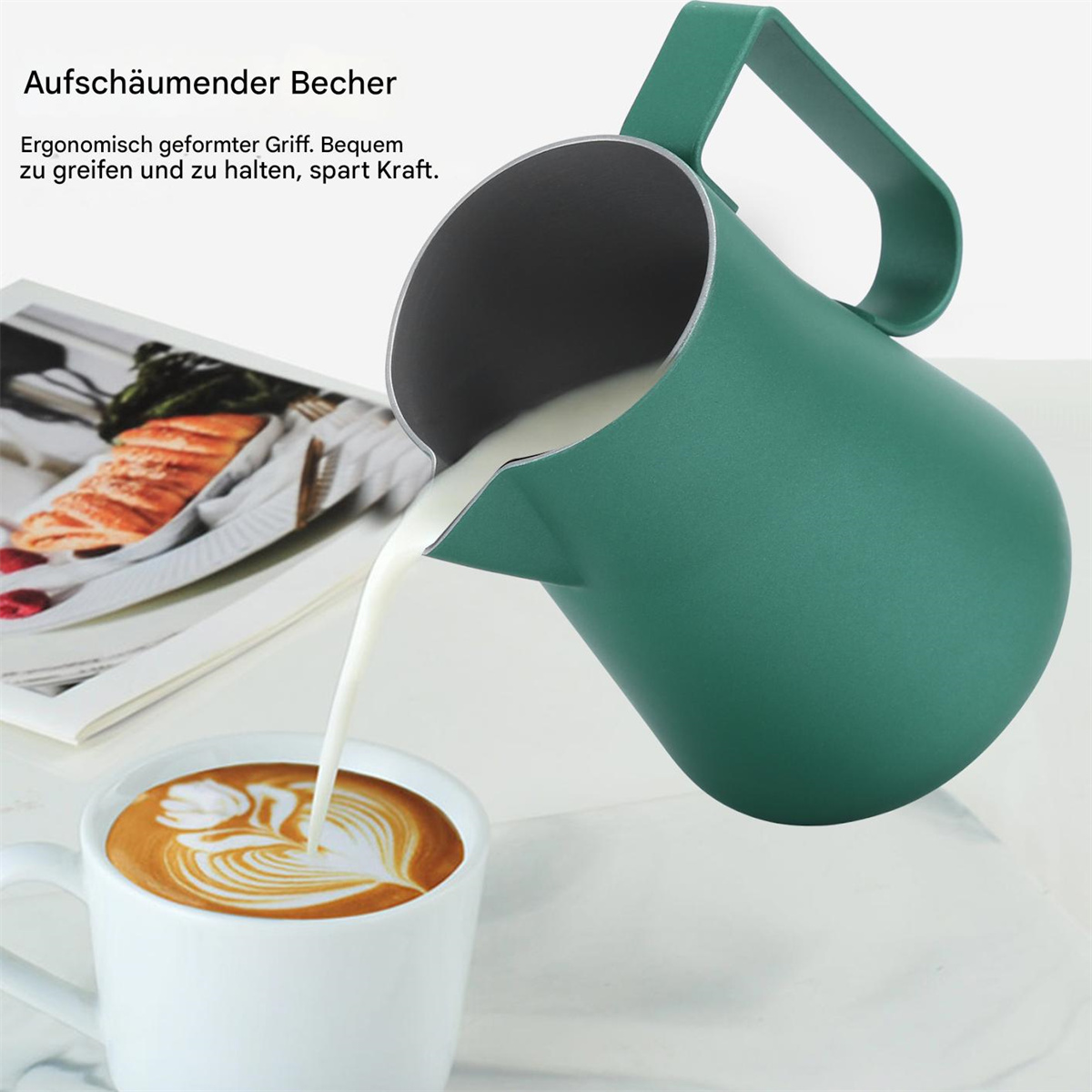 Eine grüne Milchaufschäumkanne, die Milch in eine weiße Tasse mit Latte Art gießt.