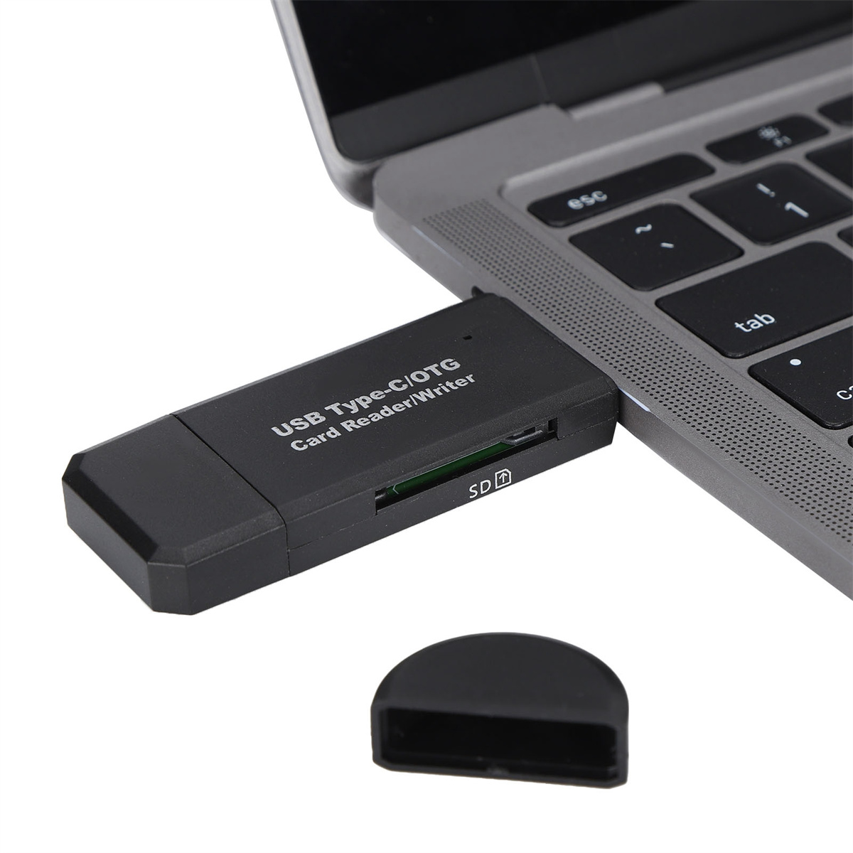 Ein schwarzer USB-C-Kartenleser, der an einen Laptop angeschlossen ist. Er hat einen SD-Kartensteckplatz und eine Kappe.