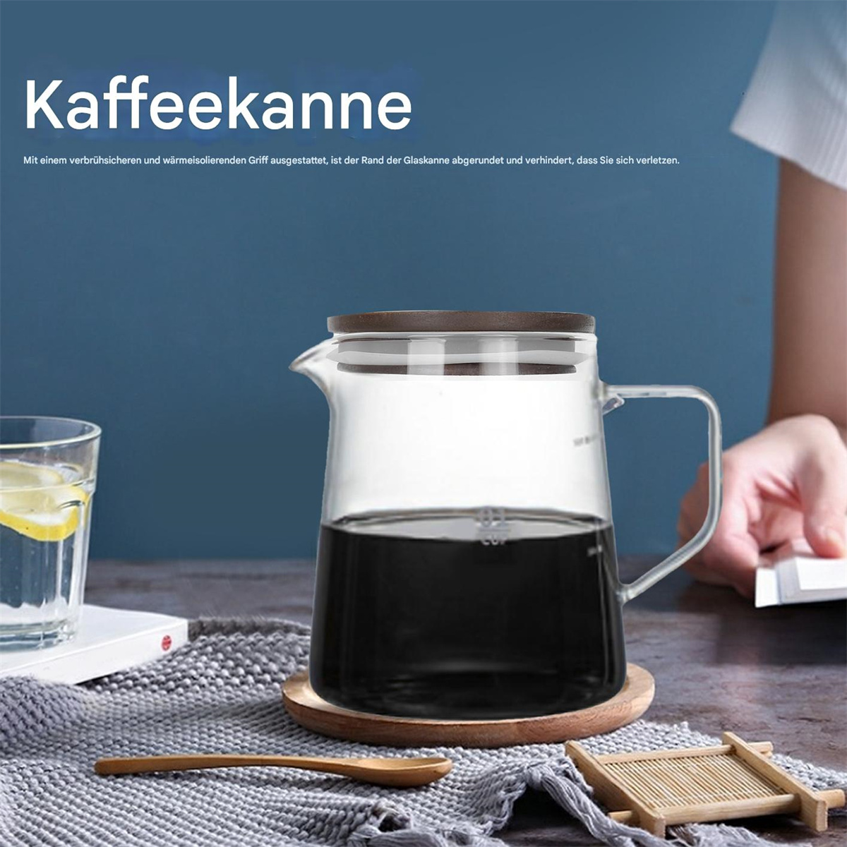 Glaskaffeekanne mit dunkler Flüssigkeit, Holzdeckel und Griff. Untersetzer, Löffel und Bambustablett im Vordergrund.