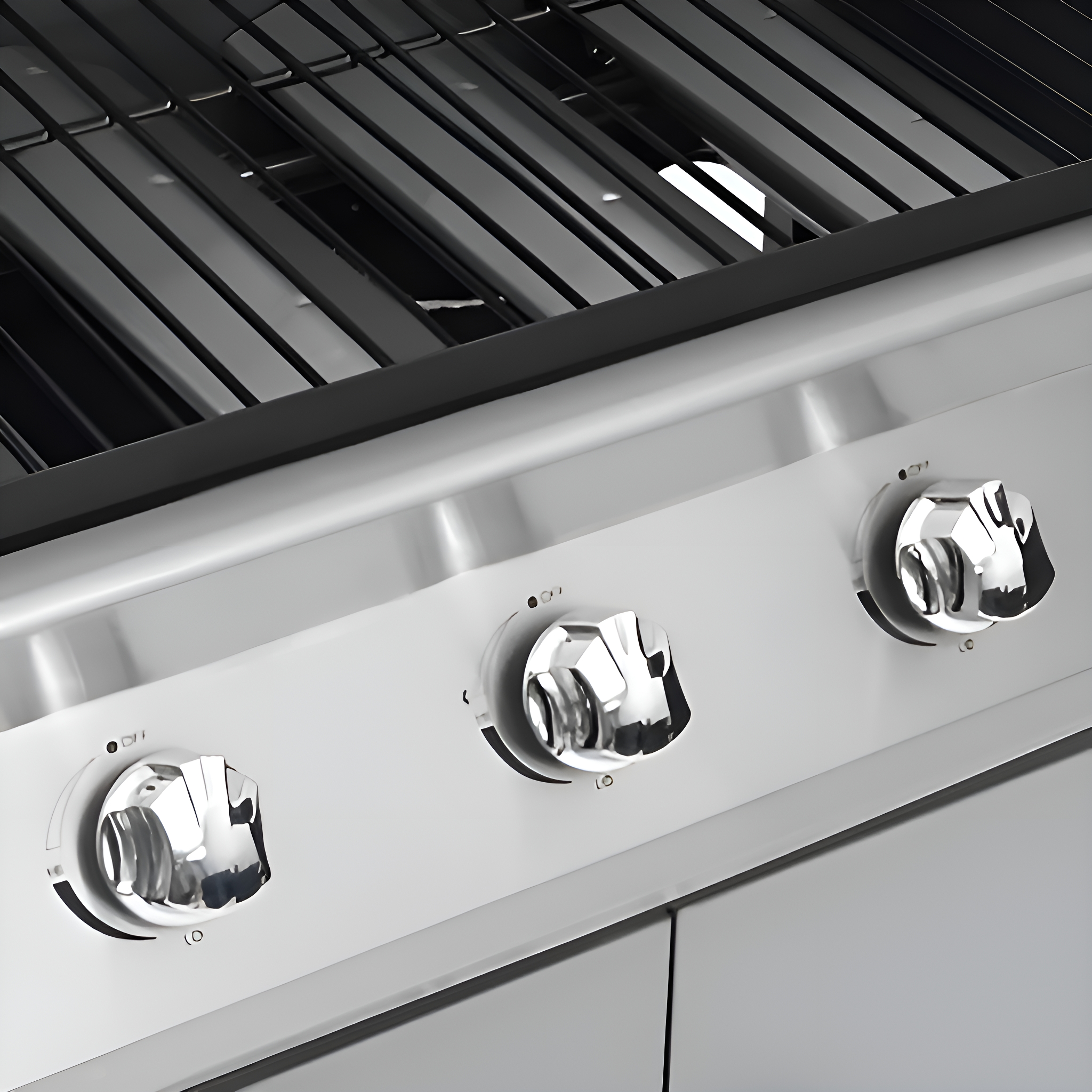 Nahaufnahme eines Edelstahlgrills mit drei Bedienknöpfen und Grillrosten im Hintergrund.
