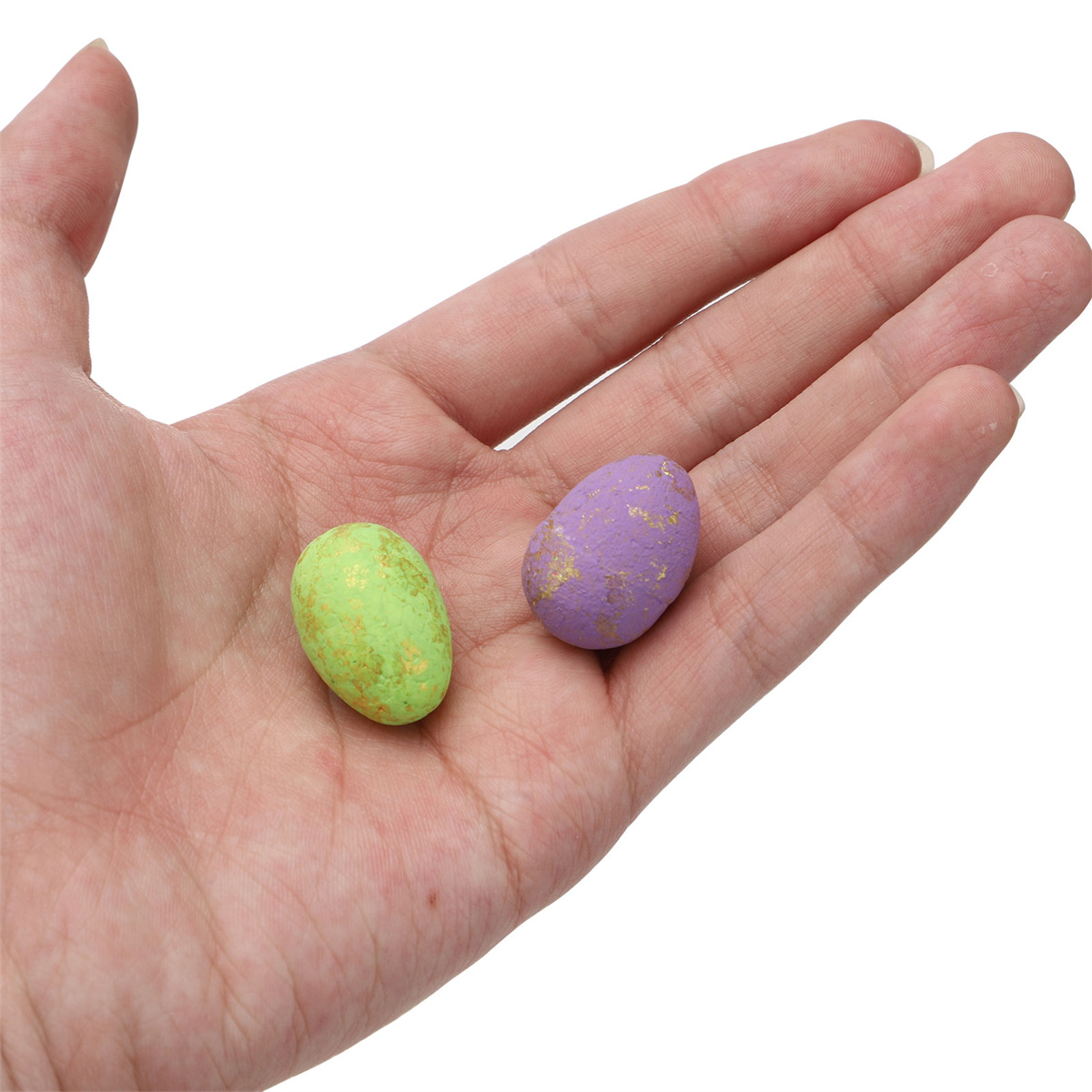Hand hält zwei bunte Ostereier, grün und lila.