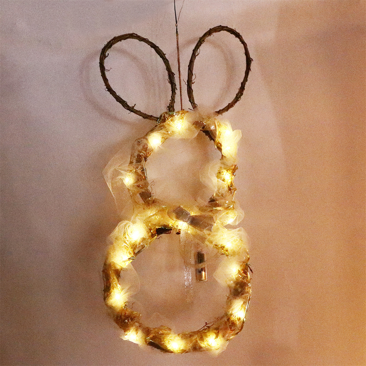 Osterhasen-Dekoration mit Lichtern, hängt an einer Wand. Aus Zweigen und Lichtern, in Hasenform.