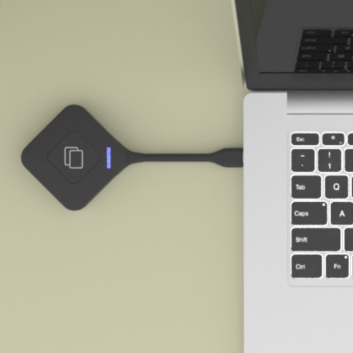 Een zwart apparaat, aangesloten op een laptop, ligt op een licht oppervlak. Het toetsenbord van de laptop is zichtbaar.