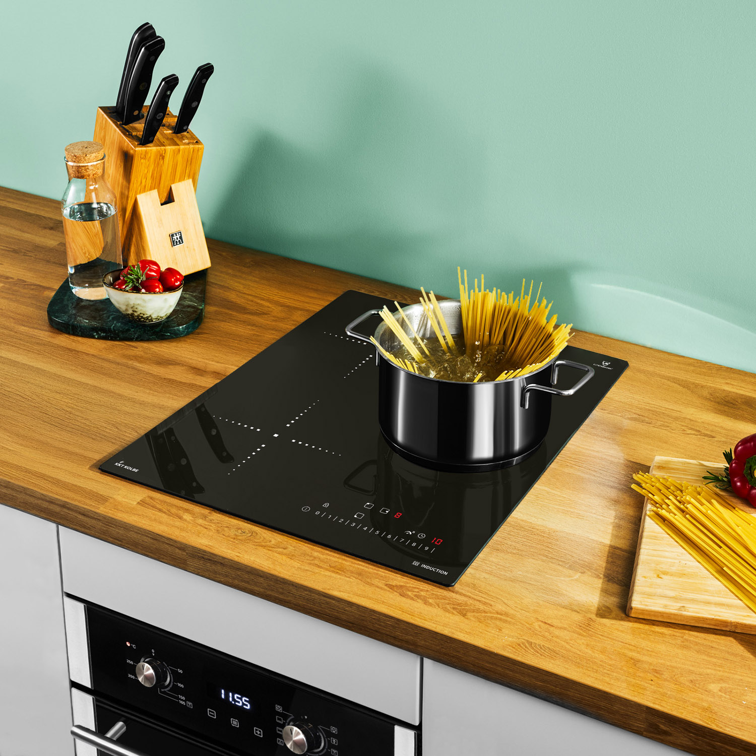 Una pentola di spaghetti cuoce su un piano cottura a induzione nero in una cucina moderna.