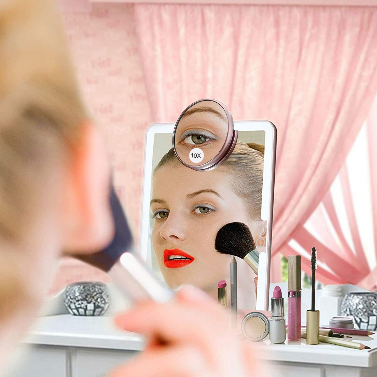 Eine Frau mit rotem Lippenstift blickt in einen Schminkspiegel. Verschiedene Make-up-Artikel stehen auf dem Tisch.