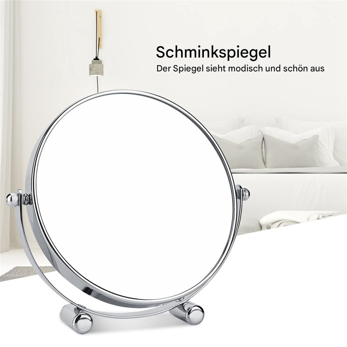 Silberner, runder Spiegel mit Ständer. Weißer Hintergrund, verschwommenes Bett im Hintergrund.