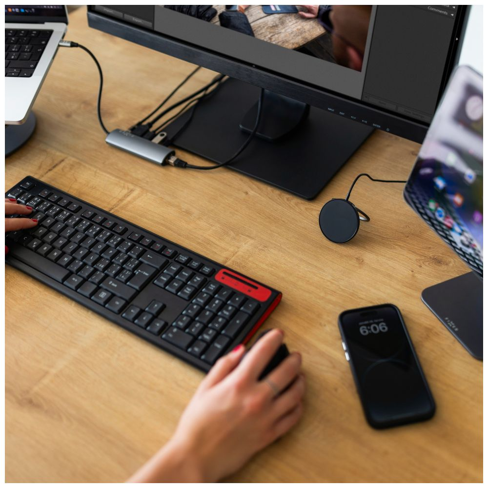 Eine Person benutzt Tastatur und Maus an einem Schreibtisch mit Telefon und Hub.