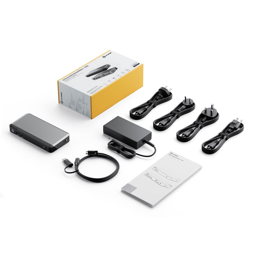 Un set di accessori per dispositivi elettronici: scatola grigia, adattatore di alimentazione nero, cavi e manuale, sfondo bianco.