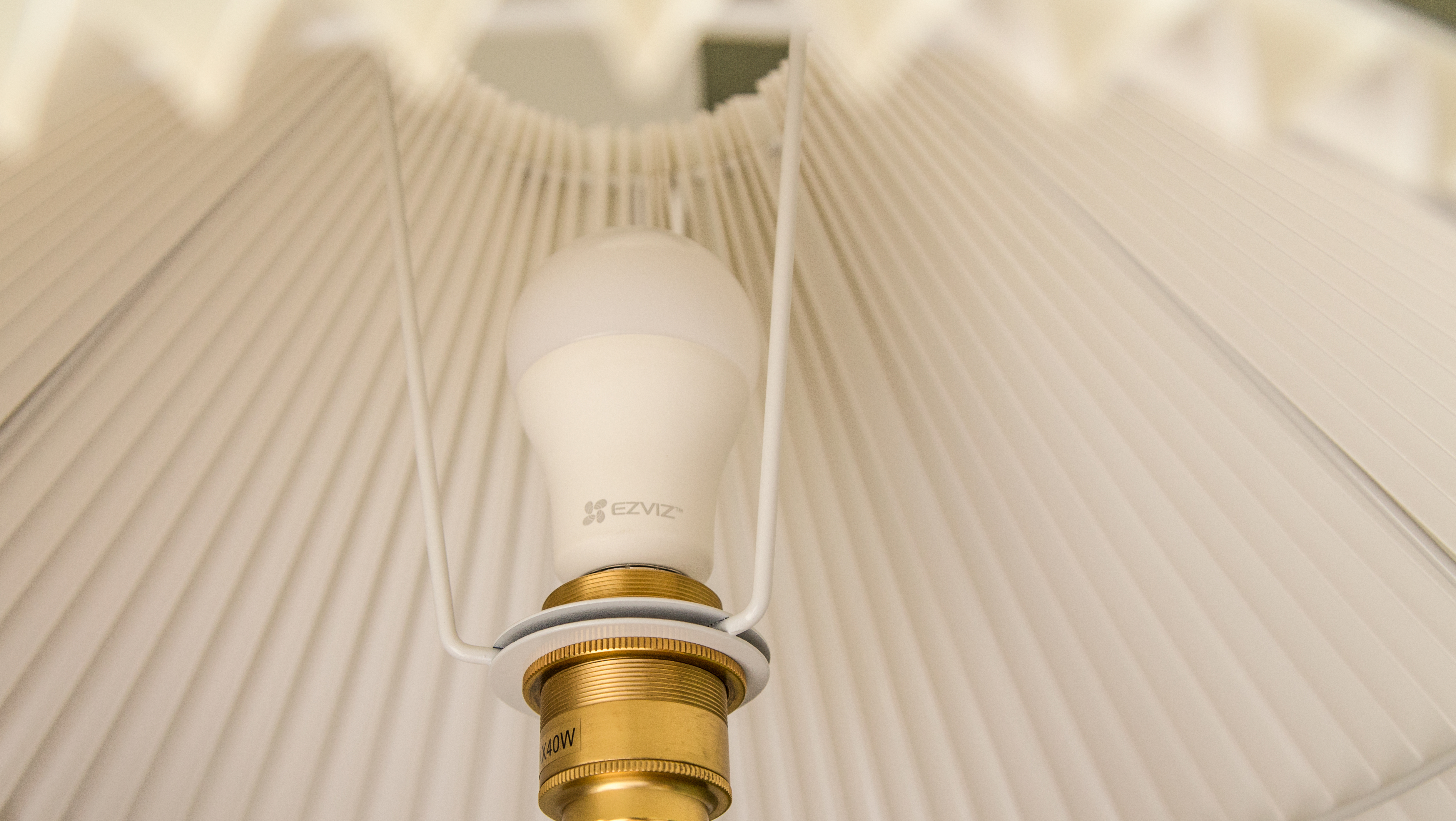 Lampadina in un paralume. Hardware della lampada dorato e bianco. Paralume plissettato bianco.