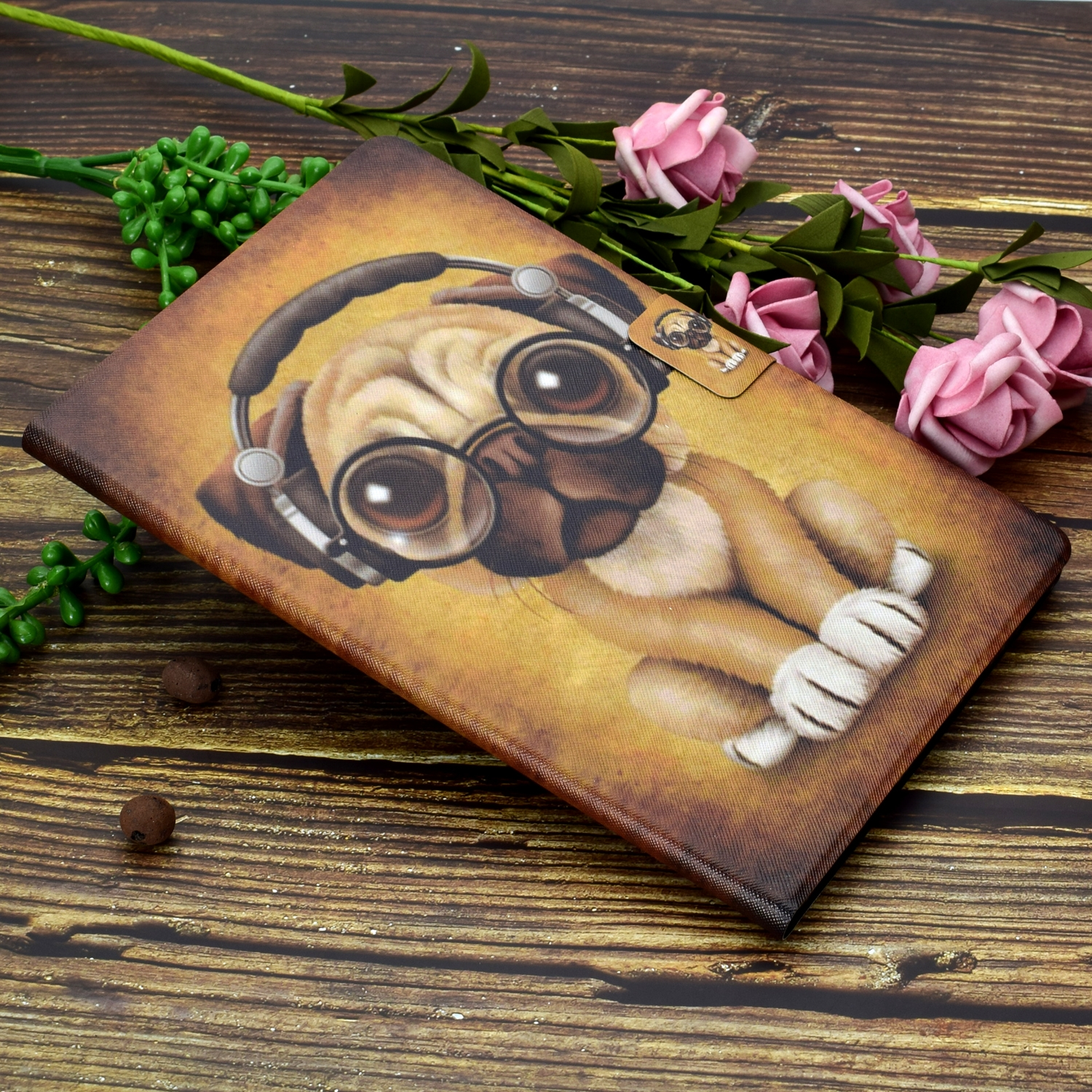 Ein Buchcover mit einem Mops mit Brille und Kopfhörern auf einer Holzoberfläche mit Blumen.