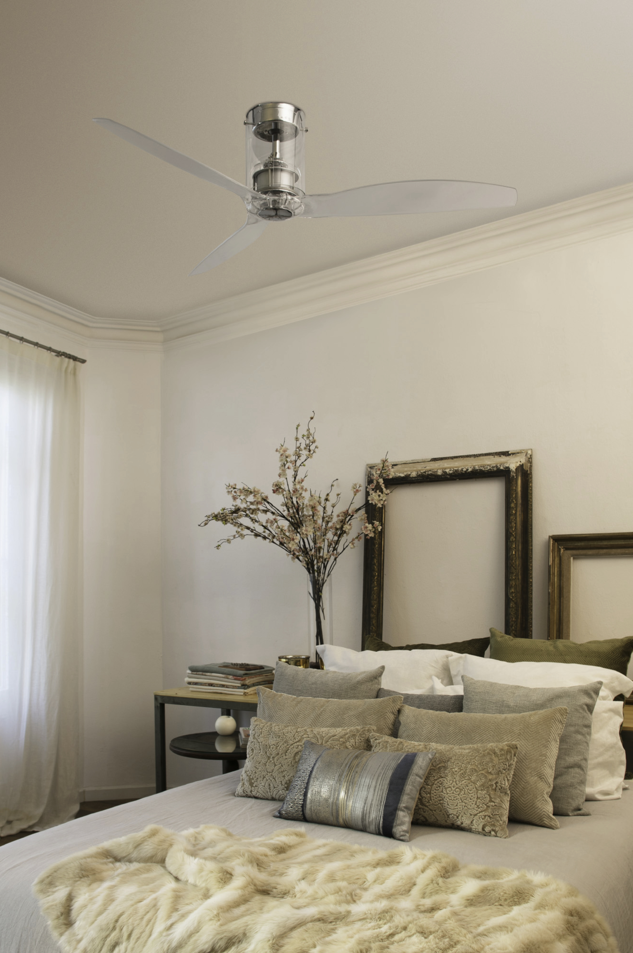 Camera da letto con ventilatore a soffitto, letto, quadri con cornice e vaso di fiori.