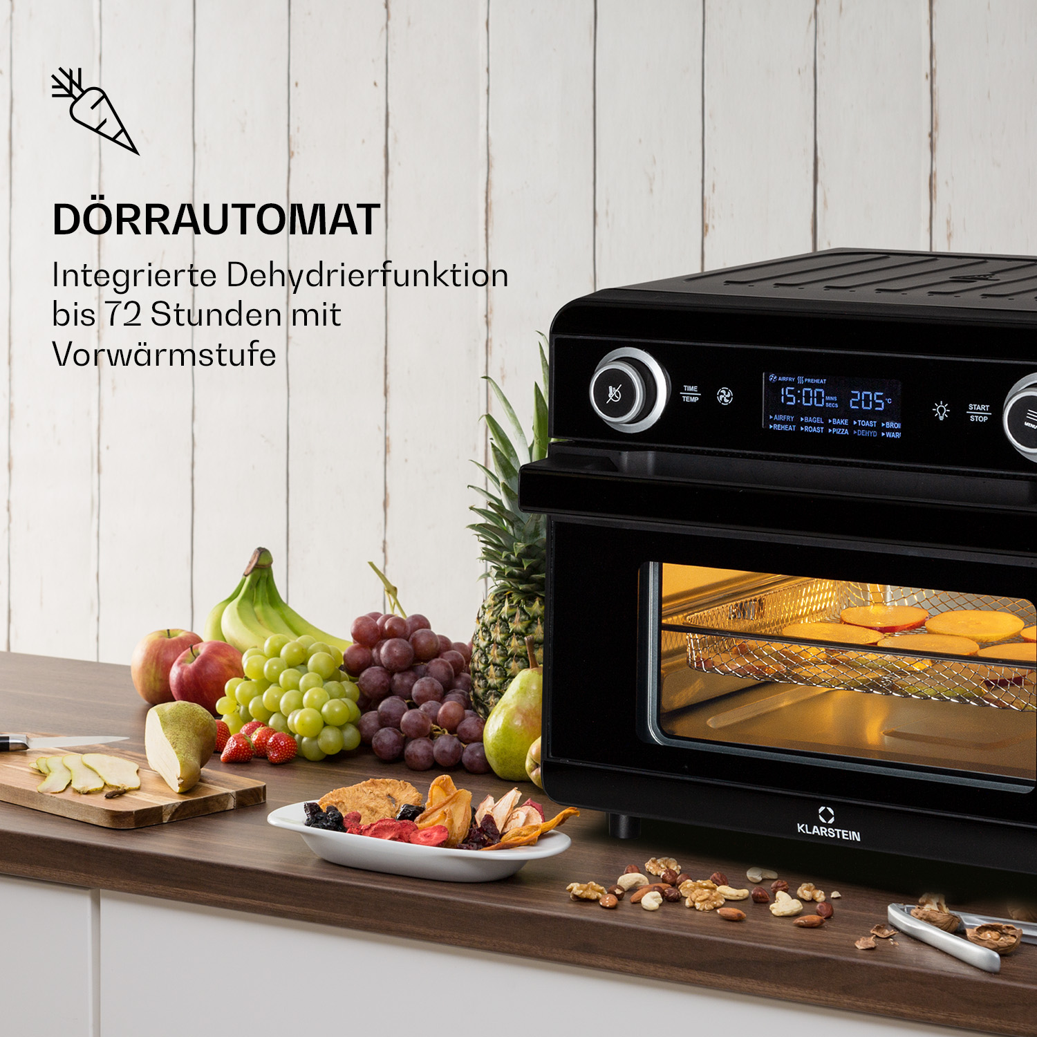 Schwarzer Ofen mit Essen darin, Obst und Gemüse auf einem Tisch, weißer Hintergrund.