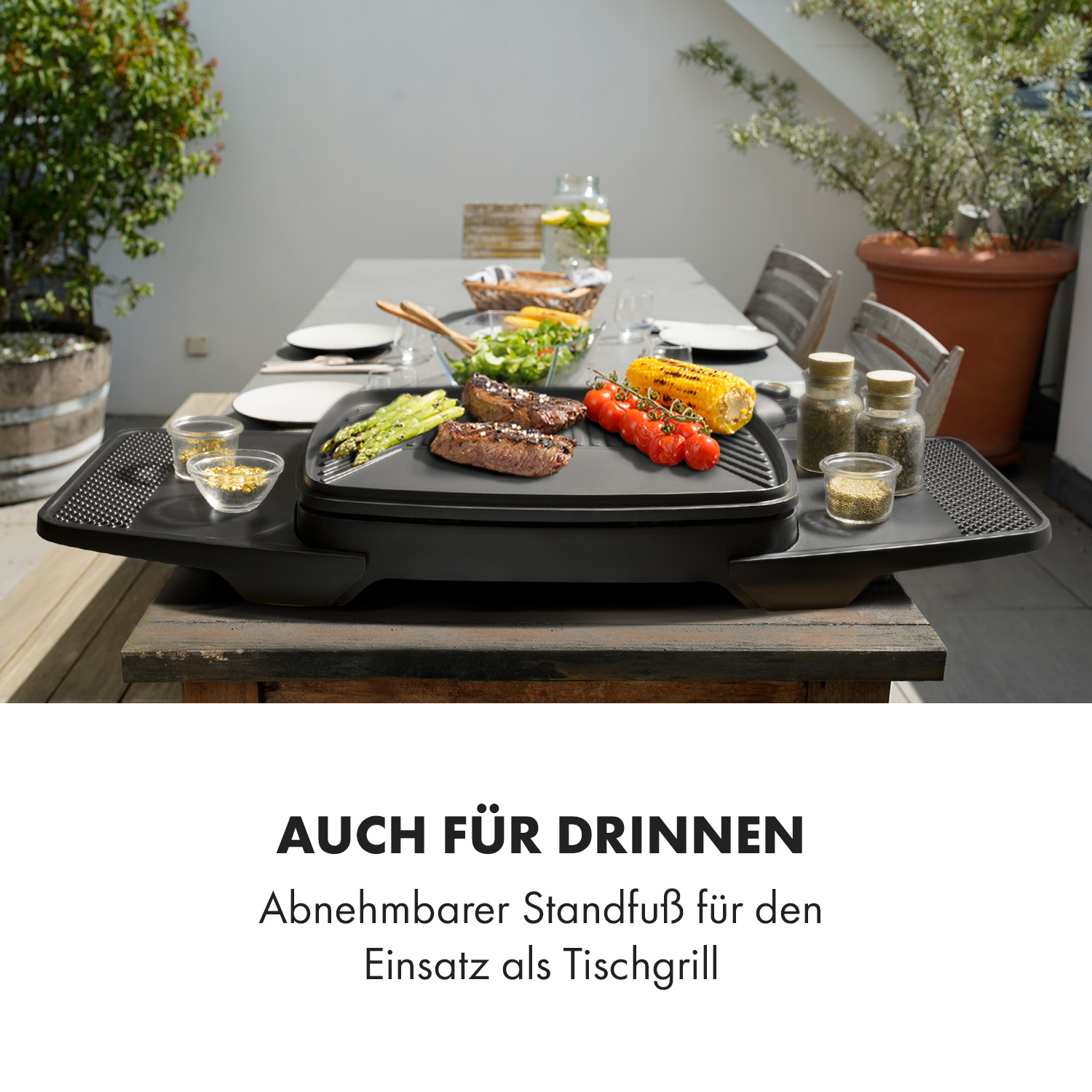 Ein Grill mit Essen auf einem Holztisch mit Pflanzen und Wasser im Hintergrund.