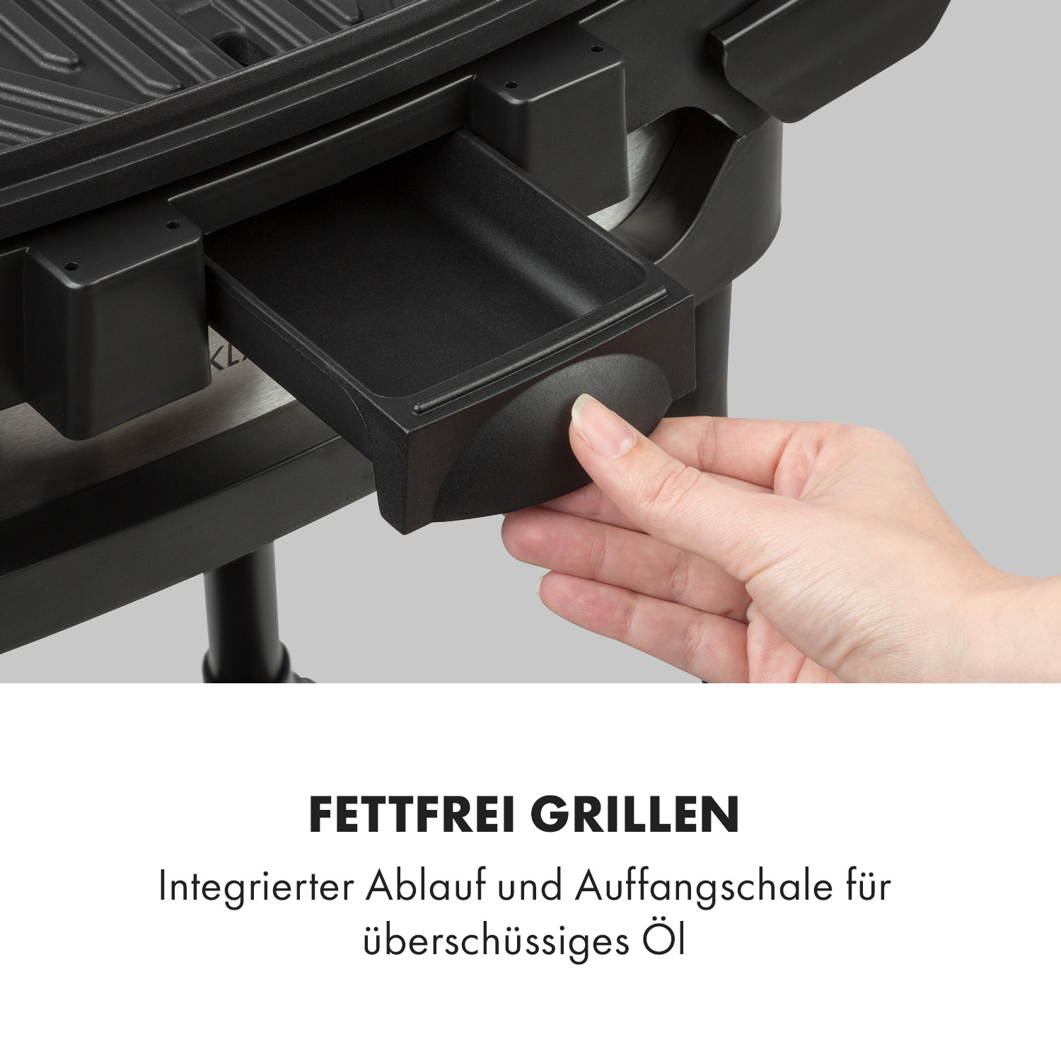 Eine Hand zieht eine schwarze Schublade aus einem schwarzen Elektrogrill.